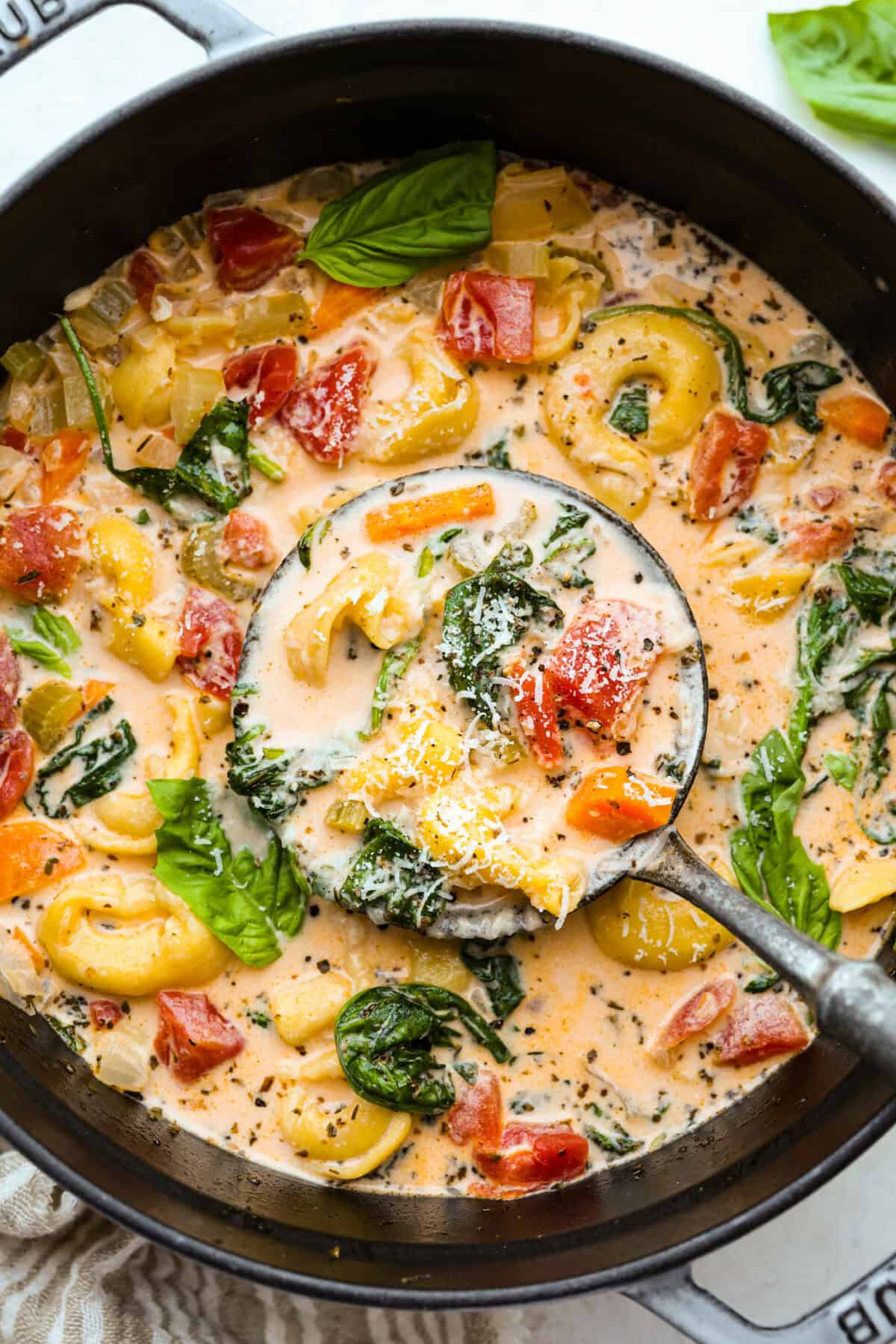 My love of cozy soups kicks in the second summer fades. This creamy tortellini soup gives me all the fall vibes. Fresh veggies, cheesy pasta, and a creamy broth, it's comfort in a bowl. Youโve got to try it today! Pot of creamy vegetable tortellini soup with a silver ladle.