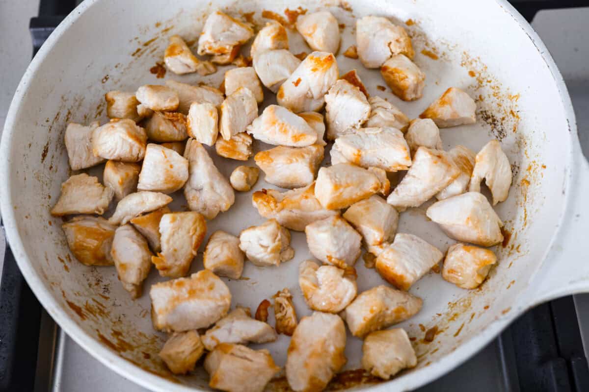 This creamy Tuscan chicken orzo bake is the kind of dinner youโll want on repeat! Tender chicken, orzo, and sun-dried tomatoes bake together in one pan for an easy, comforting weeknight meal. Cubed chicken cooking in a skillet.