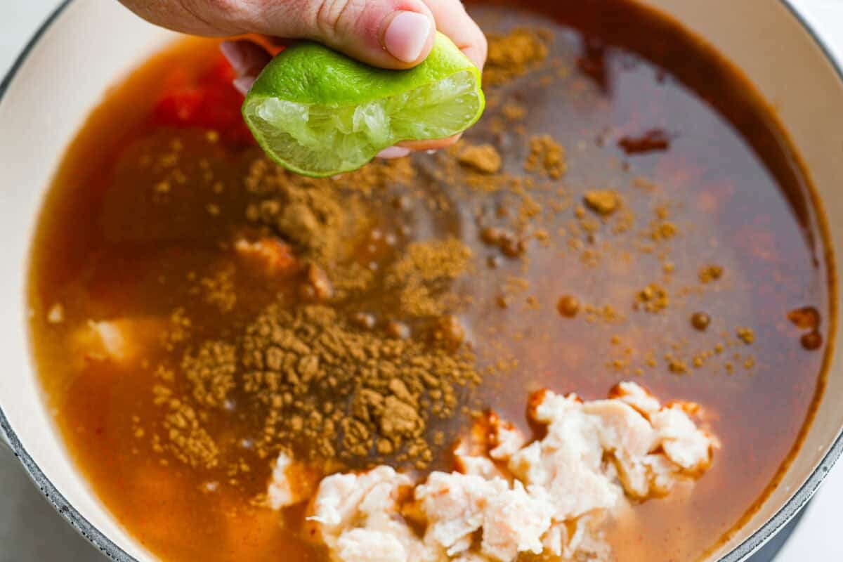 It doesn't get any easier than this 8 Can Chicken Tortilla Soup! Dinner is ready in minutes! Just open, dump, heat, and enjoy bold, delicious flavor in no time! Someone squeezing lime juice over the seasoned canned ingredients in the pot.