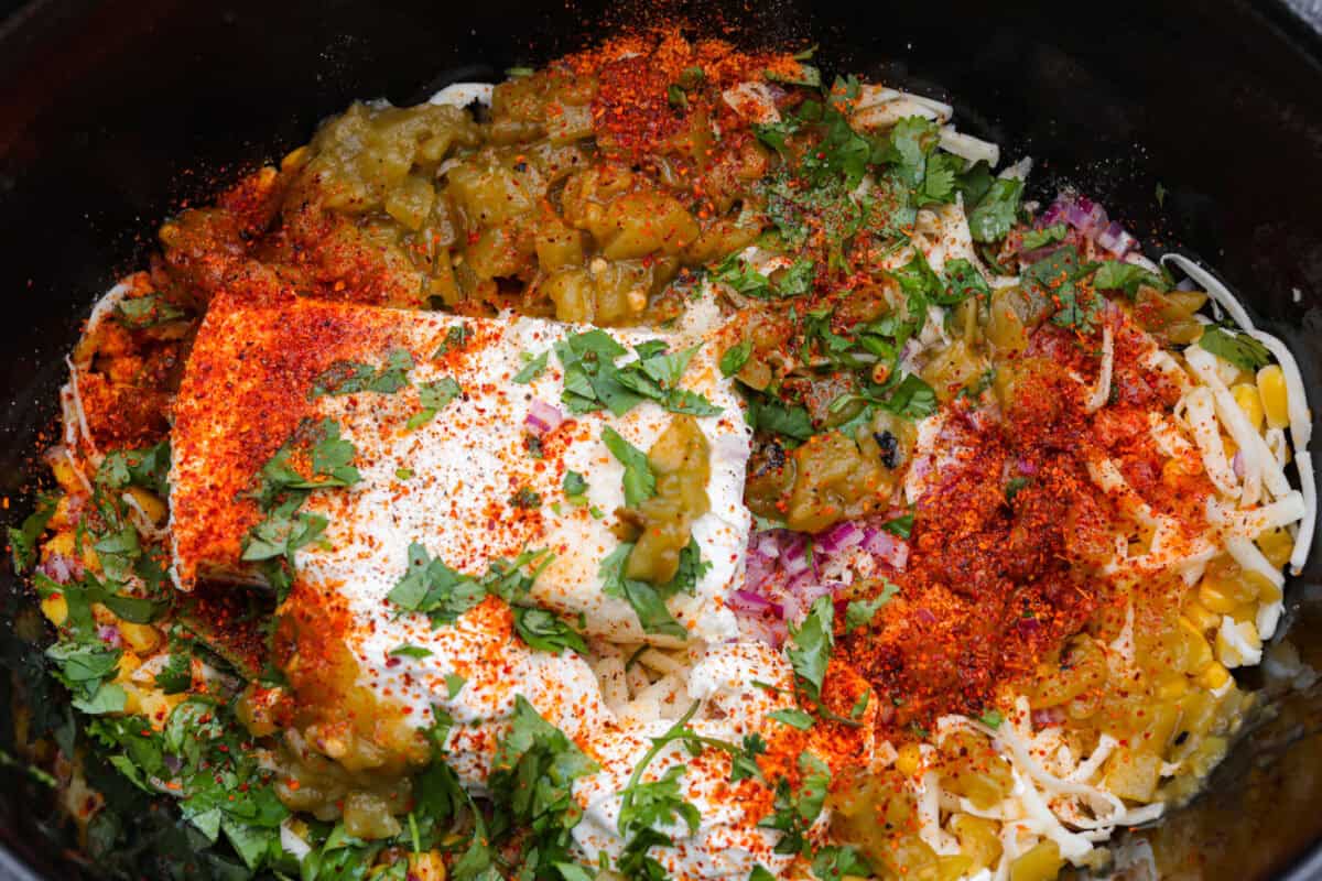 My slow cooker Mexican street corn dip takes all the flavors of elote and turns them into a warm, creamy, cheesy dip. Just toss everything in the crockpot and let it do the work. All of the ingredients added to the crockpot.