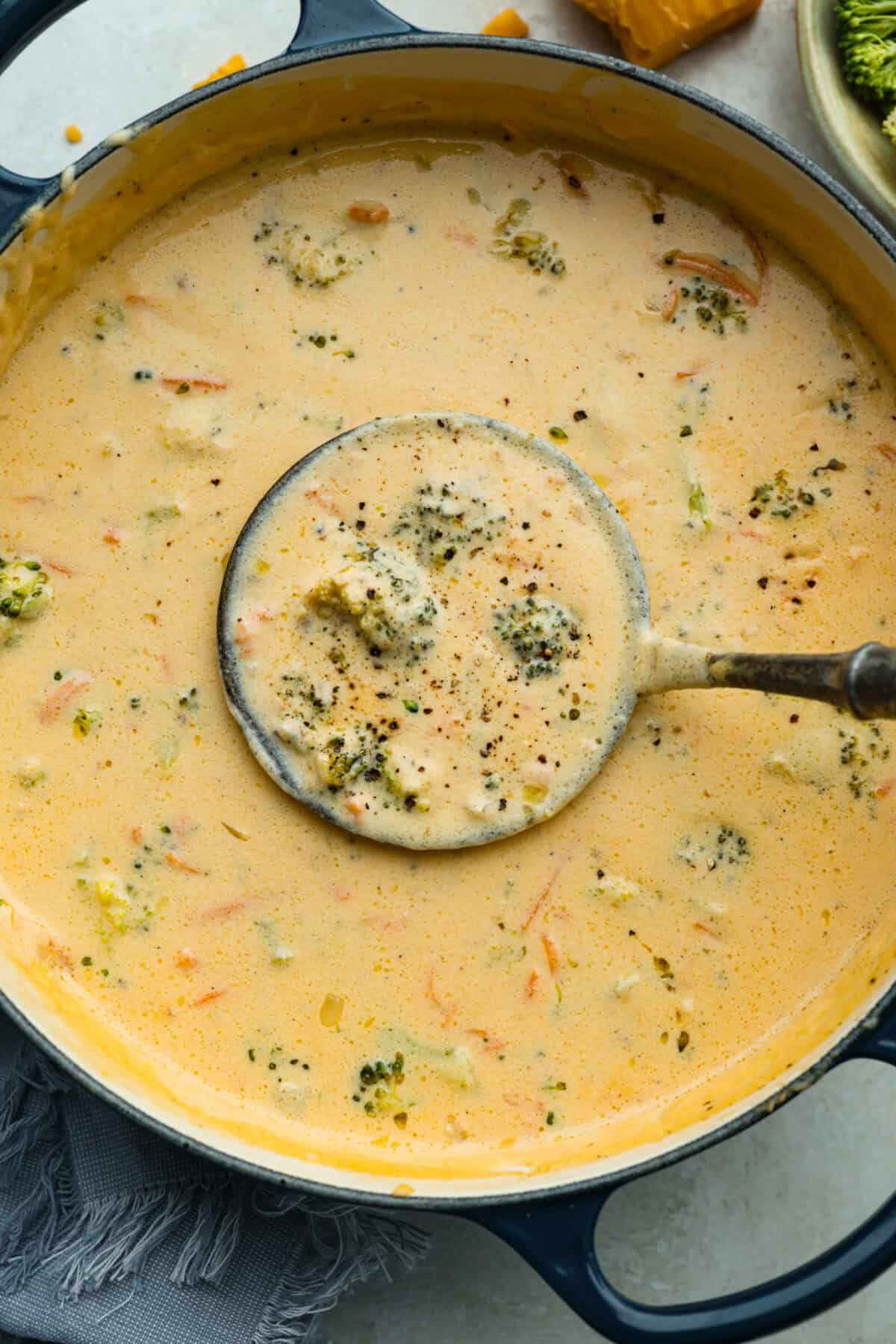 I promise that with just one bite of this copycatย Panera Breadย Broccoli Cheddar Soup, you'll be hooked! It's ultra creamy with broccoli, shredded carrots, and a hint of nutmeg, all cooked together with melted cheese. This soup is delicious and easy to make! Overhead shot of Panera broccoli cheddar soup in a pot with a ladel.