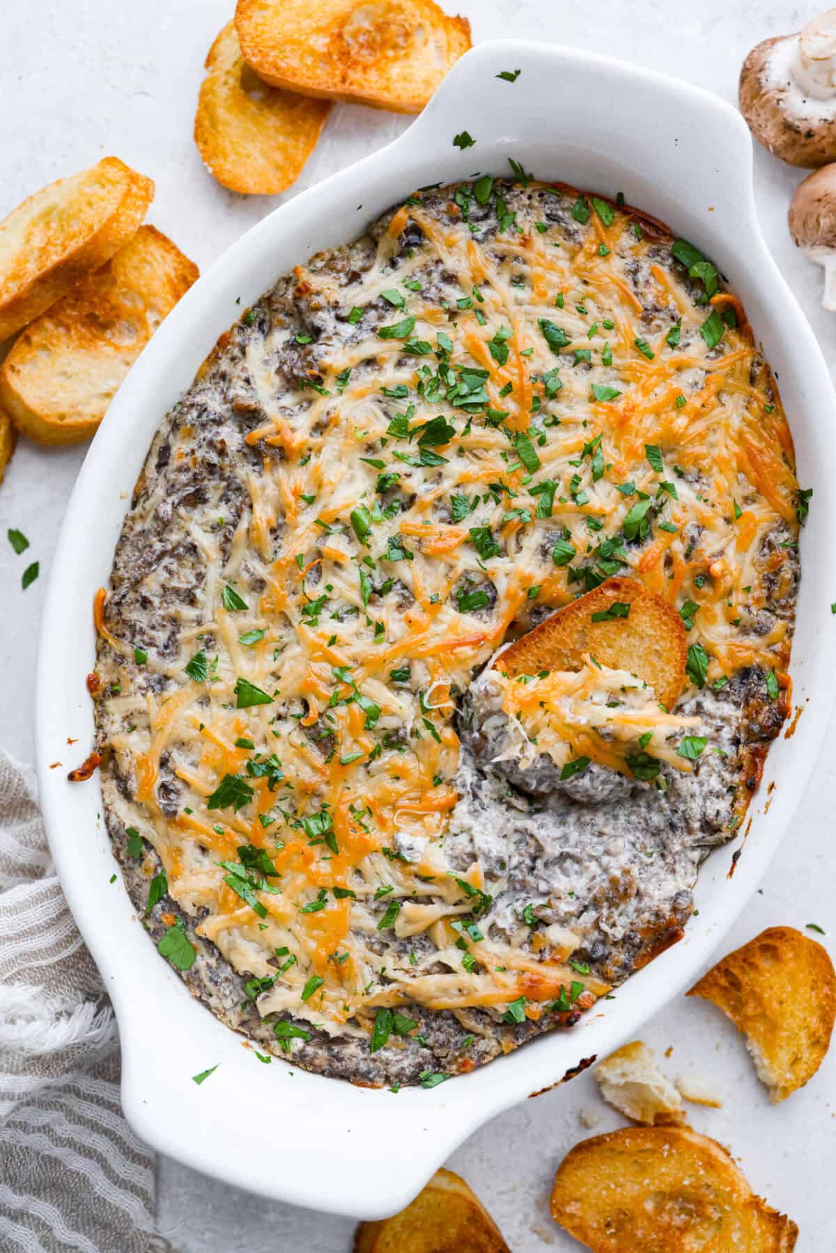 Trust me, this Stuffed Mushroom Dip is way easier (and honestly better) than making stuffed mushrooms. You skip all the filling and baking but still get that creamy, cheesy, herby, sausage flavor everyone’s obsessed with. Overhead shot of the baked stuffed mushroom dip.