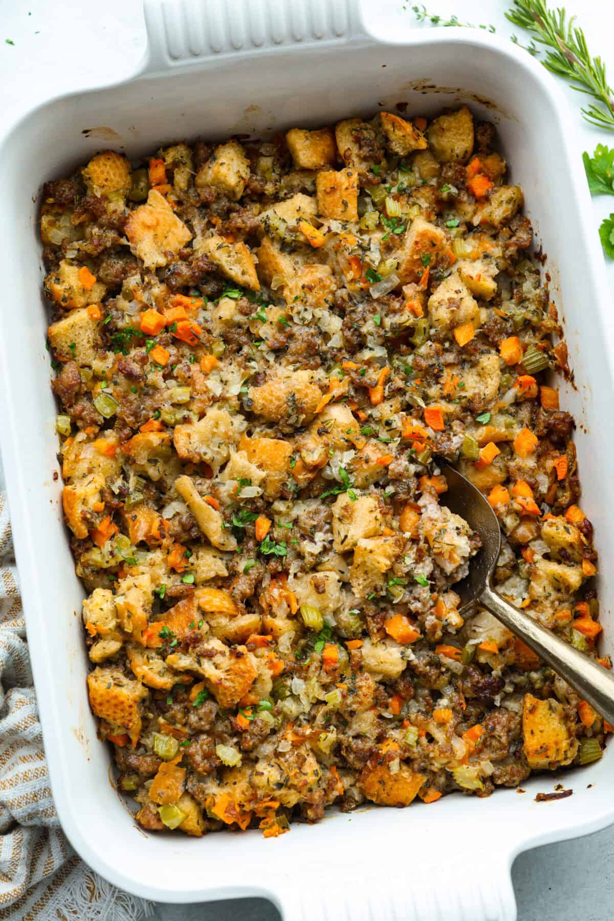 Why did it take me this long to use it in stuffing? Sourdough Stuffing's tangy crustย and the chewy middleย are perfection! Every bite soaks up all that buttery, herby goodness like it was made for this. Baking dish with sourdough stuffing and a serving spoon.