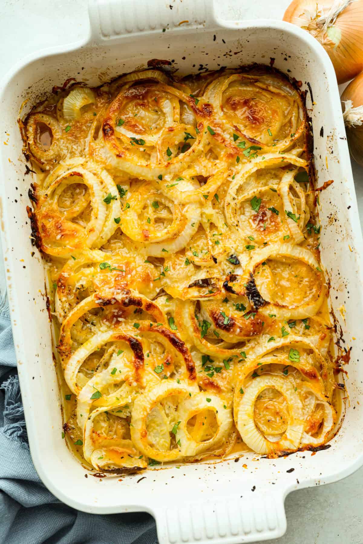 If you’ve never had Tennessee onions, bless your heart! Sweet onions bake in butter and gooey cheese until they’re golden, bubbly, and downright sinful. The perfect side to complement steak, chicken, burgers, or your favorite BBQ. Overhead shot of baked Tennessee onions in the baking dish.