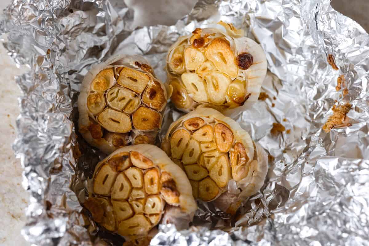 Creamy roasted garlic soup is comfort food with a side of obsession. Combining roasted garlic, tender potatoes, and nutty Parmesan into a cozy soup is absolute perfection. Just make sure you serve it to anyone within hugging distance. Roasted garlic heads in tin foil.