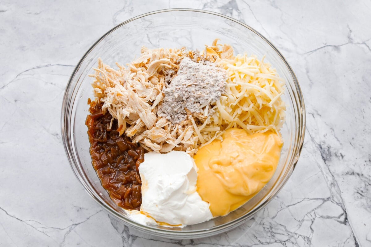 Creamy, cheesy, and packed with shredded chicken, this French onion chicken casserole is comfort food at its best! Inspired by French onion soup and dip, it’s topped with crispy fried onions for a crunchy finish. Casserole ingredients all added to a mixing bowl.