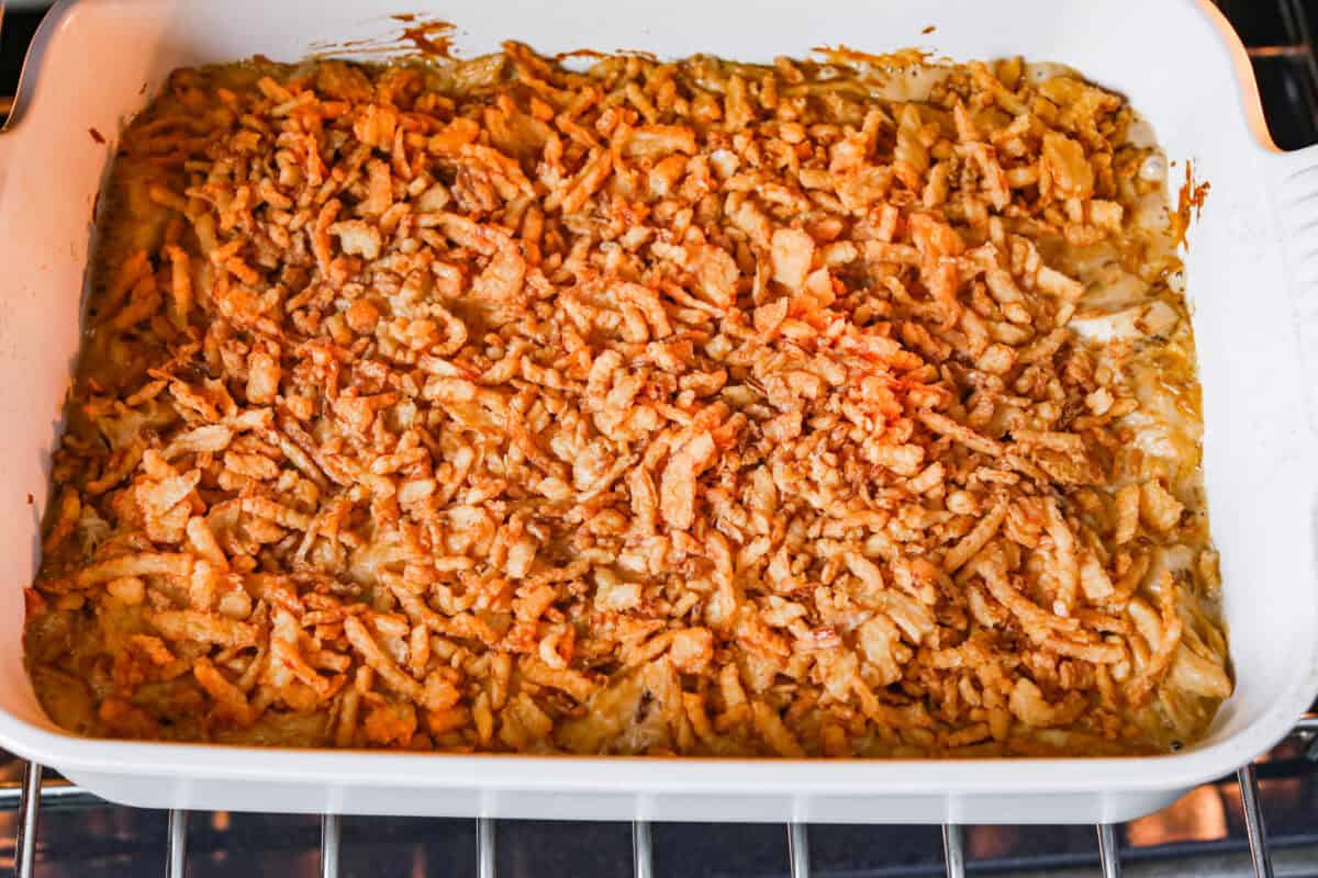 Creamy, cheesy, and packed with shredded chicken, this French onion chicken casserole is comfort food at its best! Inspired by French onion soup and dip, it’s topped with crispy fried onions for a crunchy finish. Picture of french onion chicken casserole in the oven with crispy onions added to the top.