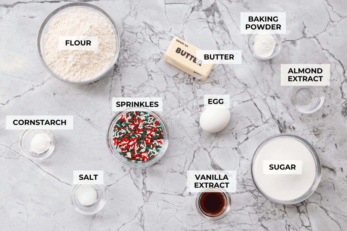 These sprinkle cookies are pure joy. Soft centers, chewy edges, and lots of colorful sprinkles! They are perfect for Christmas parties, cookie exchanges, and neighbor gifts. Overhead shot of labeled ingredients.
