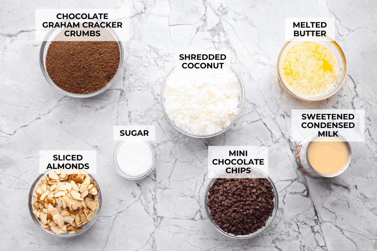 If you love coconut, chocolate, and almonds, these Almond Joy magic bars are the perfect mix. Theyโre gooey in the center, crisp on the edges, and built on a rich chocolate graham crust. Overhead shot of labeled almond joy bars ingredients.