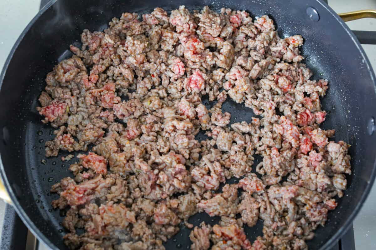 Million dollar stuffed shells take all the creamy, cheesy goodness of the classic and wrap it into fun jumbo shells. Itโs cozy, everyone loves it, and it's easyย to make! Ground beef and Italian sausage cooking in a skillet.