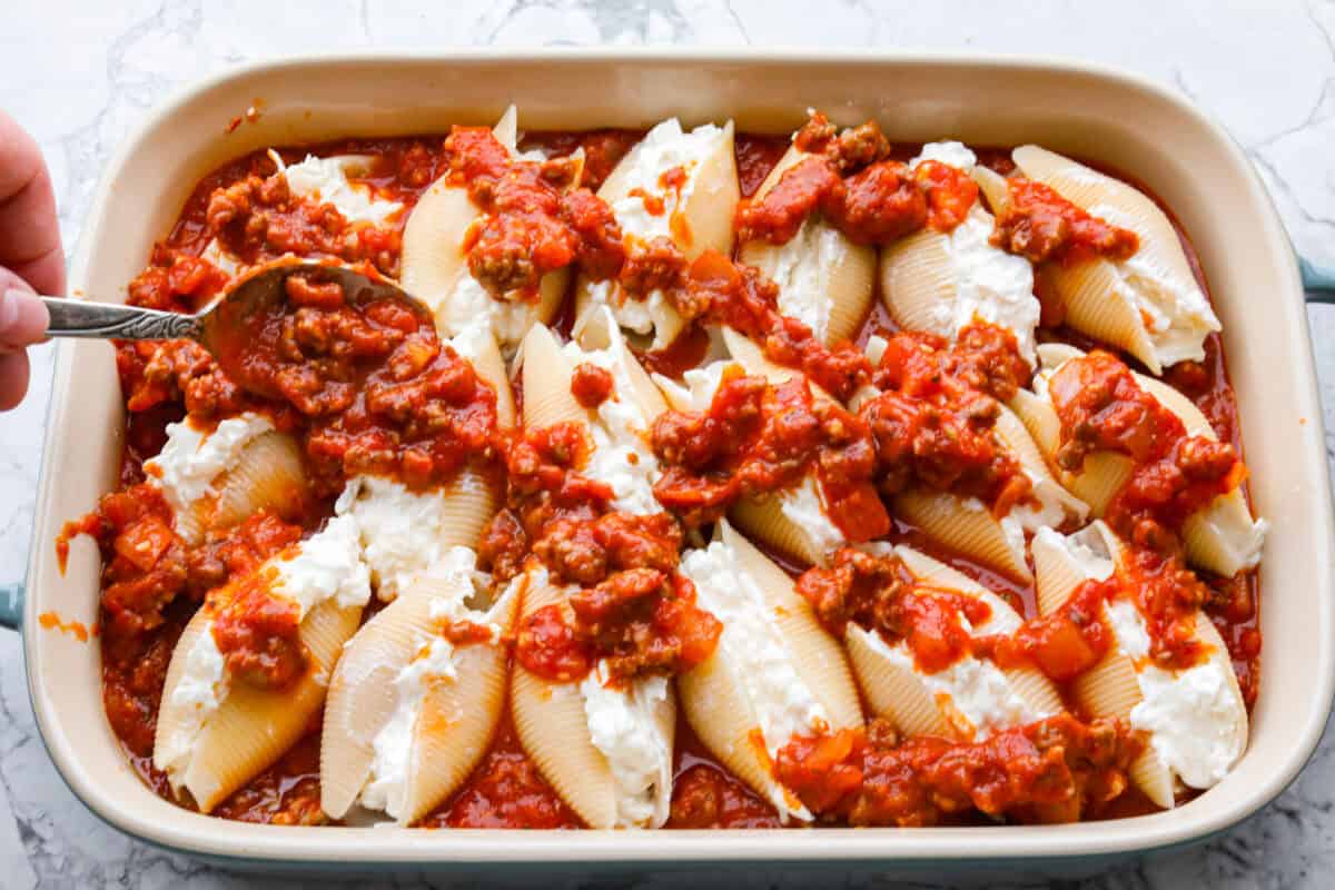 https://www.target.com/p/rao-39-s-homemade-marinara-sauce-premium-quality-all-natural-tomato-sauce-38-pasta-sauce-keto-friendly-38-carb-conscious-24oz/-/A-13349580#lnk=sametab Someone spooning more marinara mixture to the top of the million dollar stuffed shells.