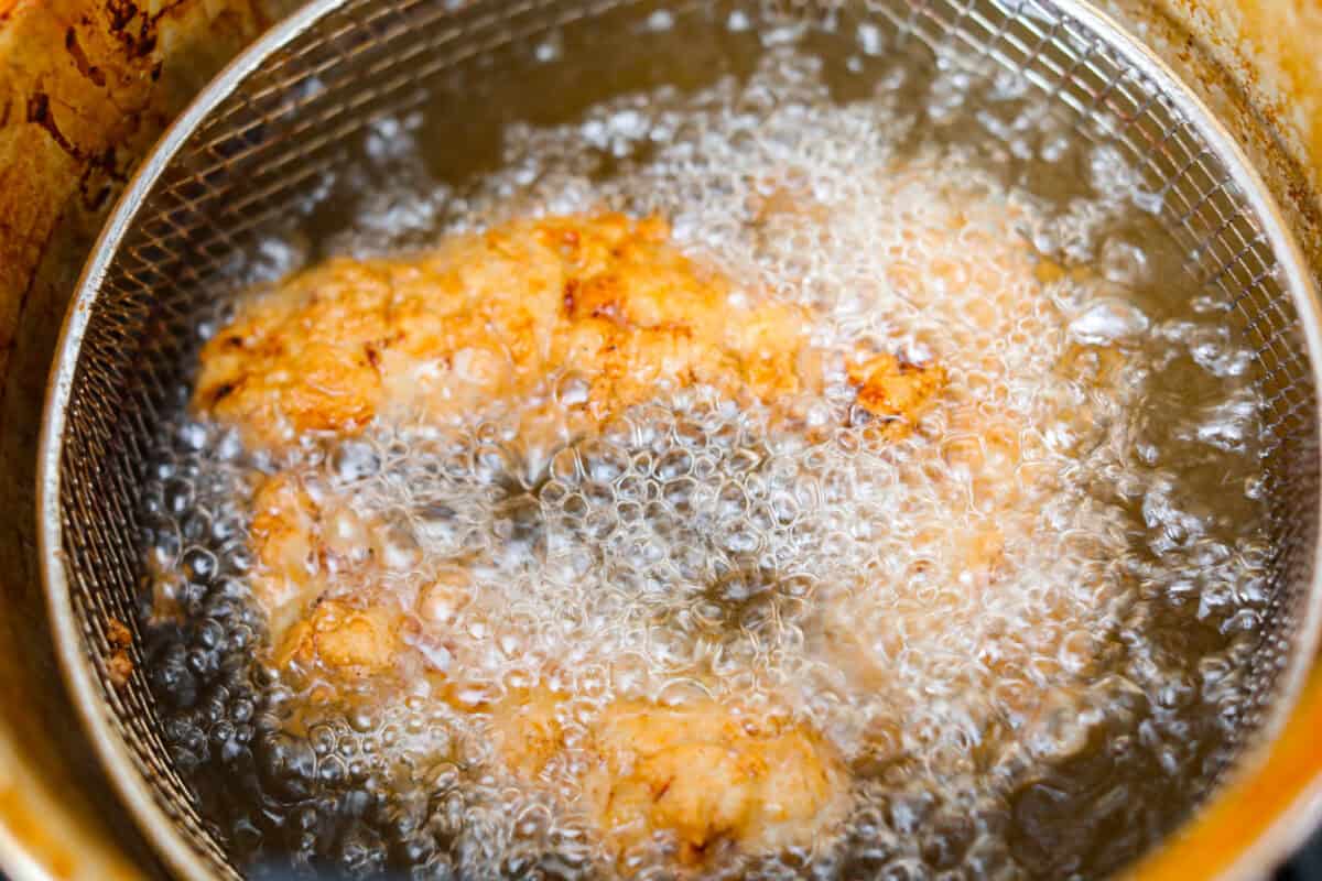 Make this copycat Raising Cane’s chicken tenders at home, no drive-thru required. An easy marinade, simple ingredients, and a quick fry give you crisp, light chicken and that unmistakable Cane’s sauce for a fraction of the cost. Raising Cane's chicken frying in a fryer.