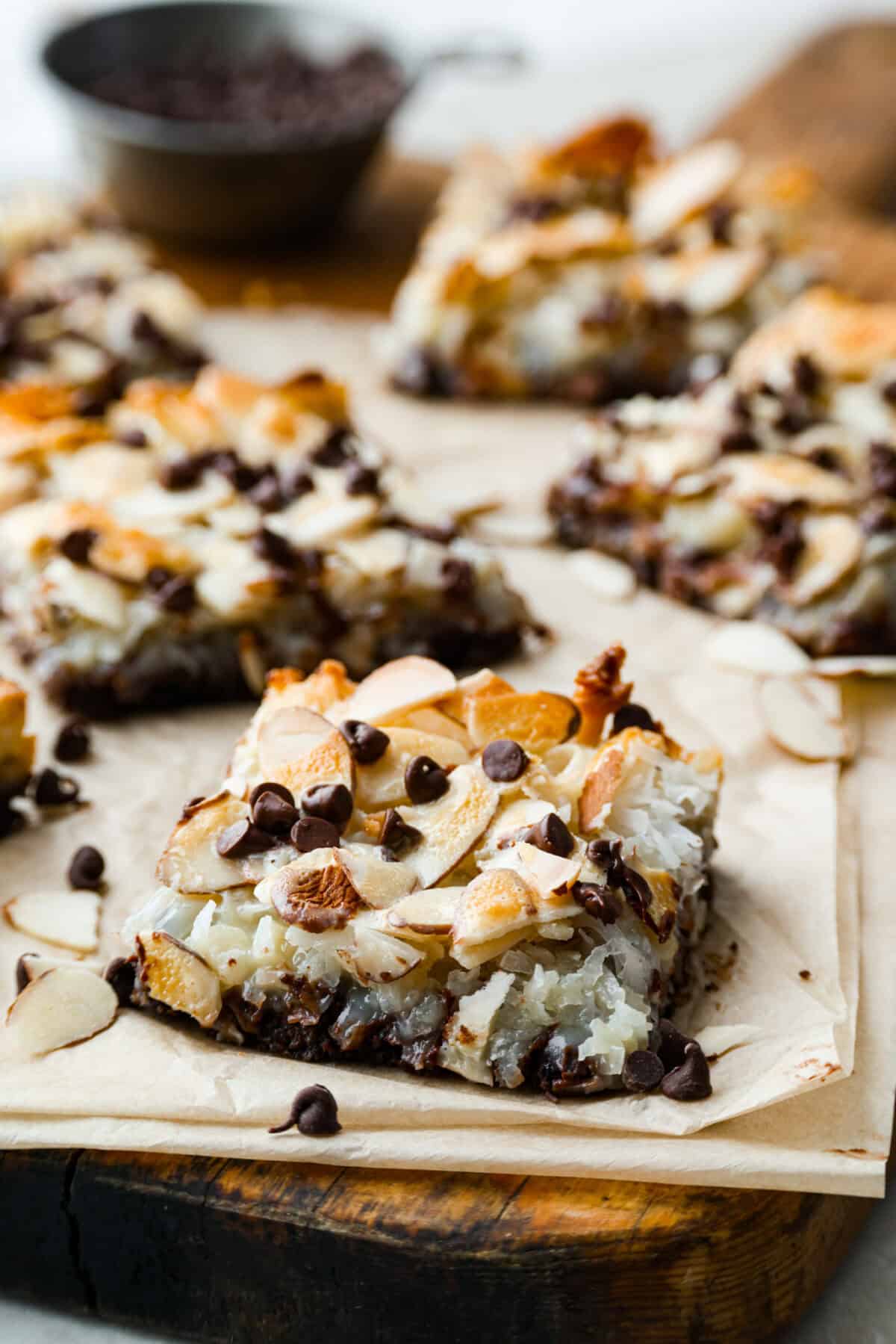 If you love coconut, chocolate, and almonds, these Almond Joy magic bars are the perfect mix. Theyโre gooey in the center, crisp on the edges, and built on a rich chocolate graham crust. Angle shot of the almond joy magic bars on a cutting board.