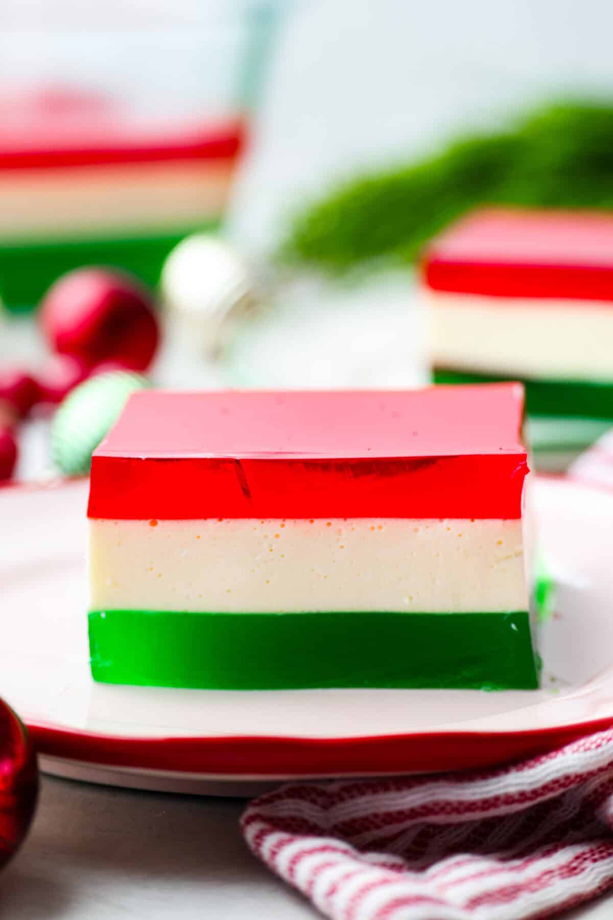 This Christmas ribbon salad brings all the festive vibes with its bright, sliceable layers. It looks fancy, but the process is super easy and mostly hands-off. Make it ahead and watch it disappear! Side shot of a slice of layer Christmas ribbon salad.