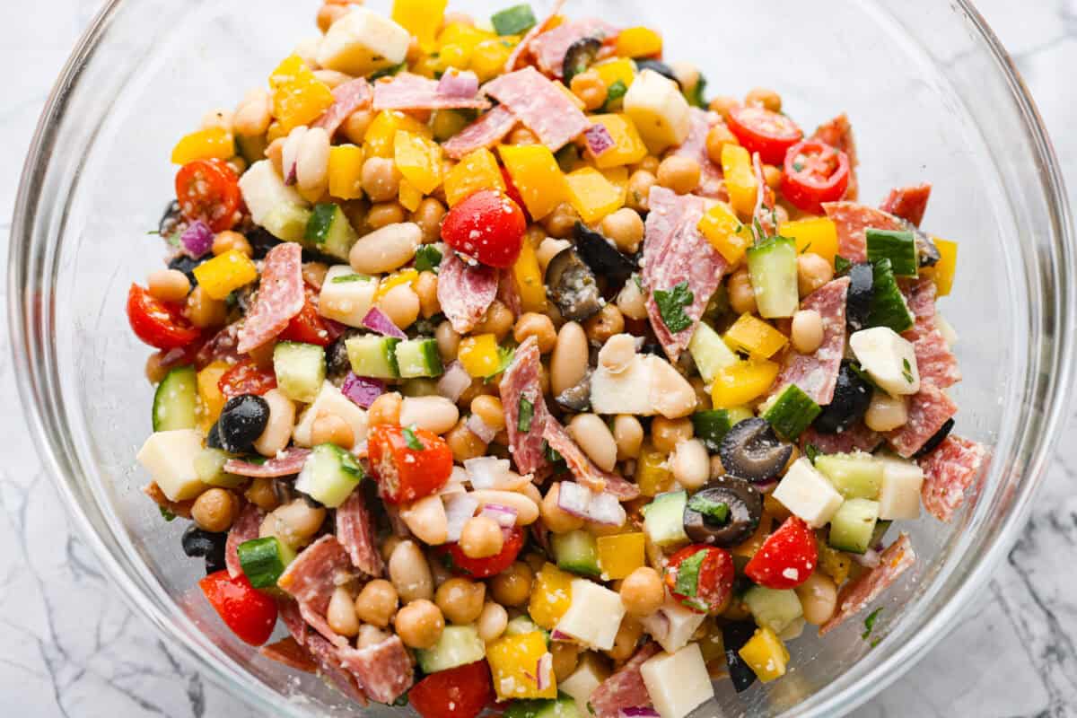 TikTok creator Violet Witchel made this dense bean salad go viral for good reason. Itโs simple, high in fiber, protein-packed, and stays delicious for days. My version keeps the same hearty texture and zesty flavor that made her trend explode. Large bowl of dense bean salad ingredients all mixed together.