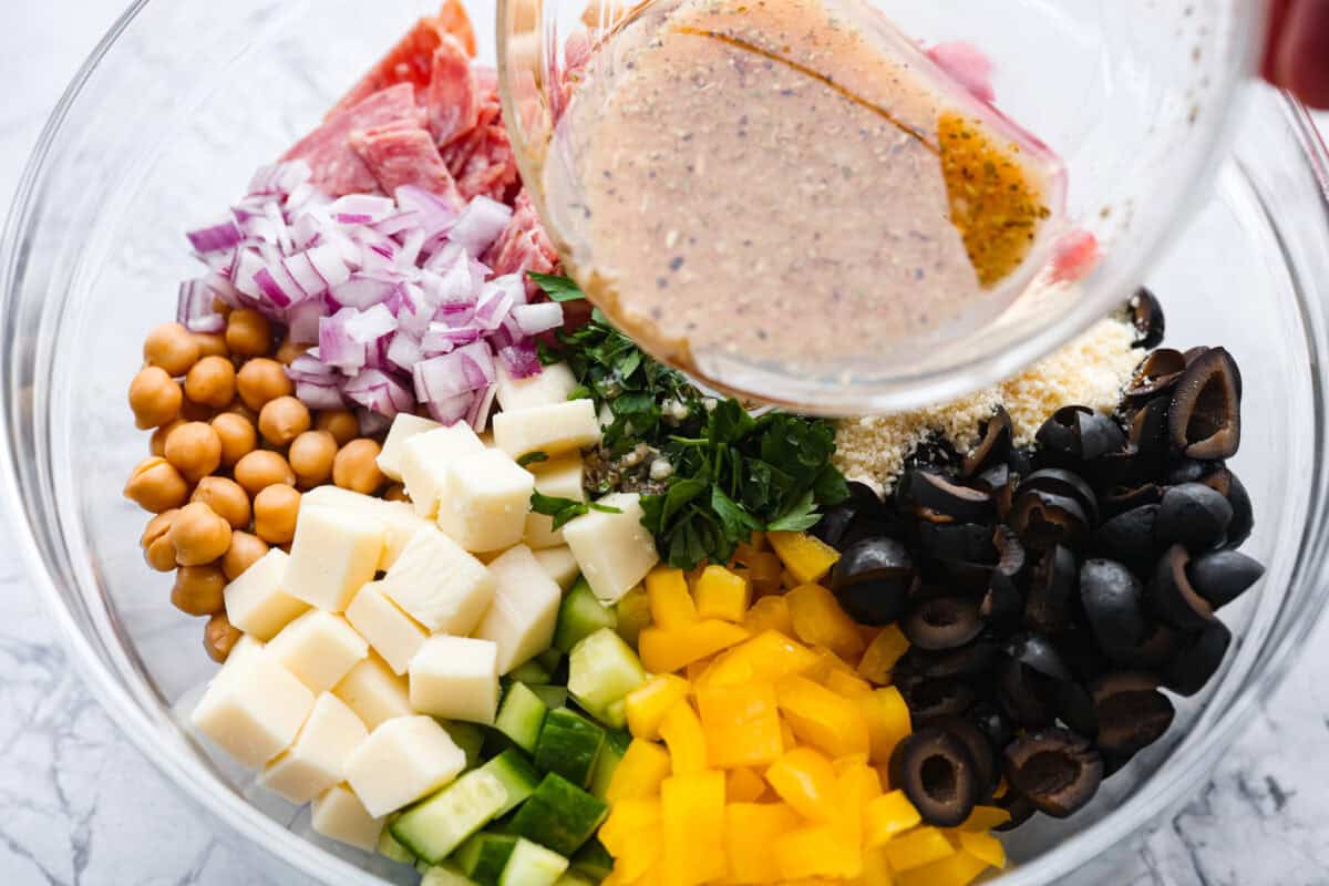 TikTok creator Violet Witchel made this dense bean salad go viral for good reason. Itโs simple, high in fiber, protein-packed, and stays delicious for days. My version keeps the same hearty texture and zesty flavor that made her trend explode. Someone pouring the dressing over the large bowl of salad ingredients.