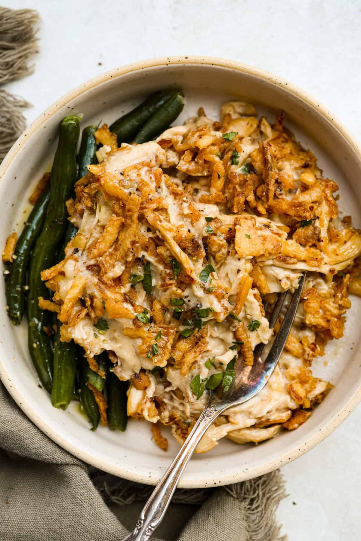 Creamy, cheesy, and packed with shredded chicken, this French onion chicken casserole is comfort food at its best! Inspired by French onion soup and dip, it’s topped with crispy fried onions for a crunchy finish. Plated French onion chicken casserole with a side of green beans.