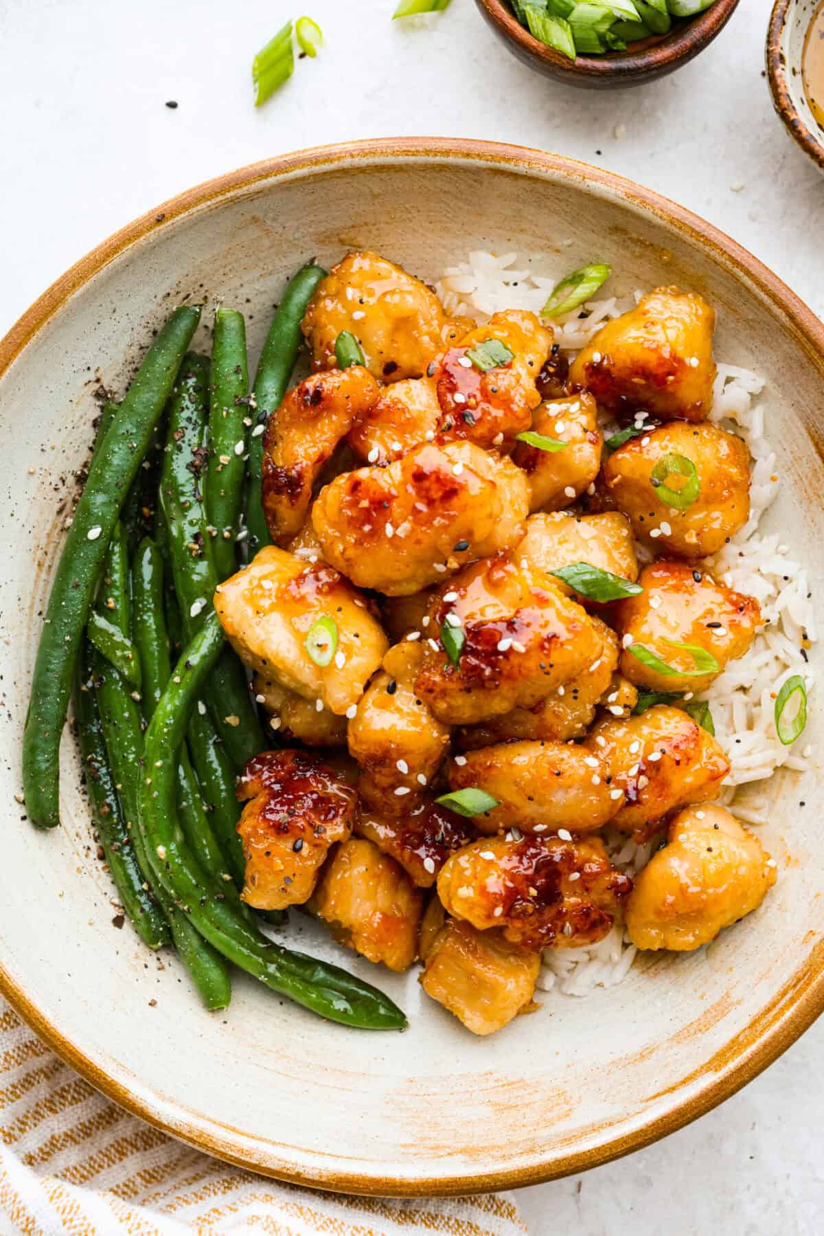 Sticky, sweet, and totally irresistible, this honey butter chicken brings golden perfection to your dinner table in just 30 minutes. One pan, picky-eater approved, and guaranteed to have everyone begging for seconds. Plated honey butter chicken over rice next to green beans.
