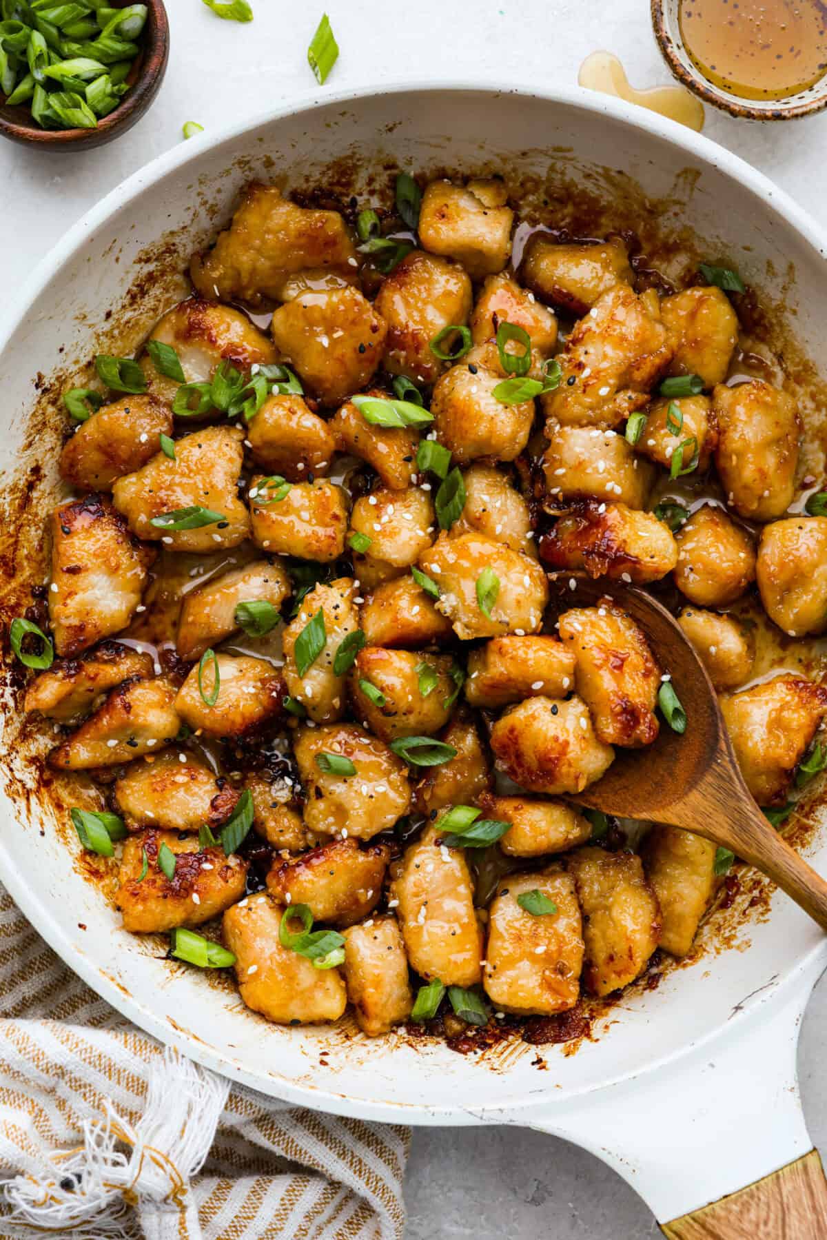 Sticky, sweet, and totally irresistible, this honey butter chicken brings golden perfection to your dinner table in just 30 minutes. One pan, picky-eater approved, and guaranteed to have everyone begging for seconds. Overhead shot of honey butter chicken in a skillet garnished with sesame seeds and green onions.