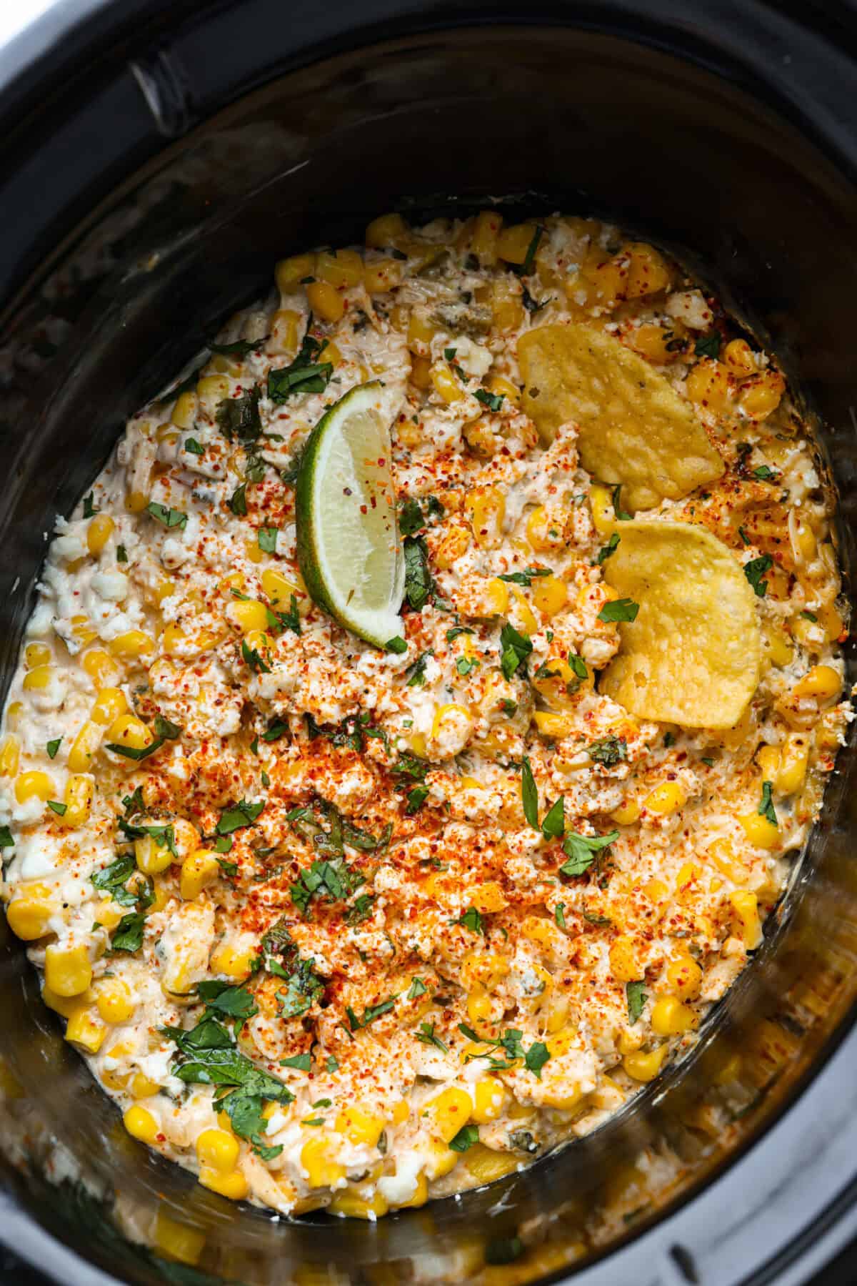 My slow cooker Mexican street corn dip takes all the flavors of elote and turns them into a warm, creamy, cheesy dip. Just toss everything in the crockpot and let it do the work. Overhead shot of Mexican street corn dip in a slow cooker.
