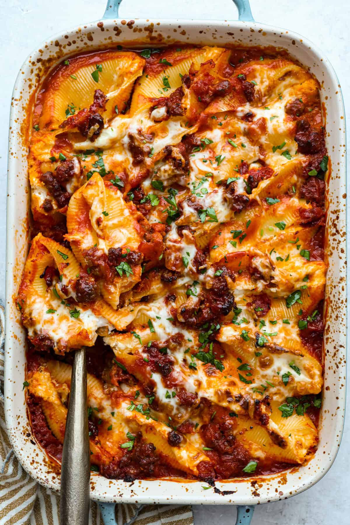 Million dollar stuffed shells take all the creamy, cheesy goodness of the classic and wrap it into fun jumbo shells. Itโs cozy, everyone loves it, and it's easyย to make! Overhead shot of the baked million dollar stuffed shells in a baking dish.