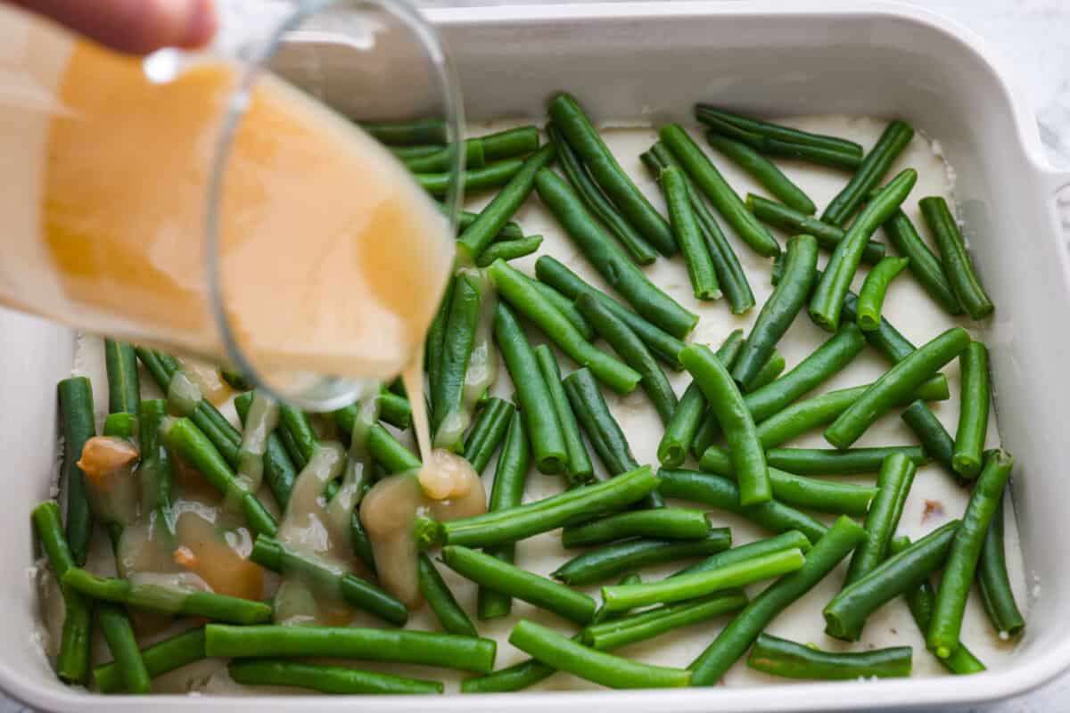 This Thanksgiving leftover casserole is the best way to enjoy every last bit of your holiday meal. I give you tips for keeping it moist, flavorful, and perfectly layered. Gravy being poured over the top of the green beans.