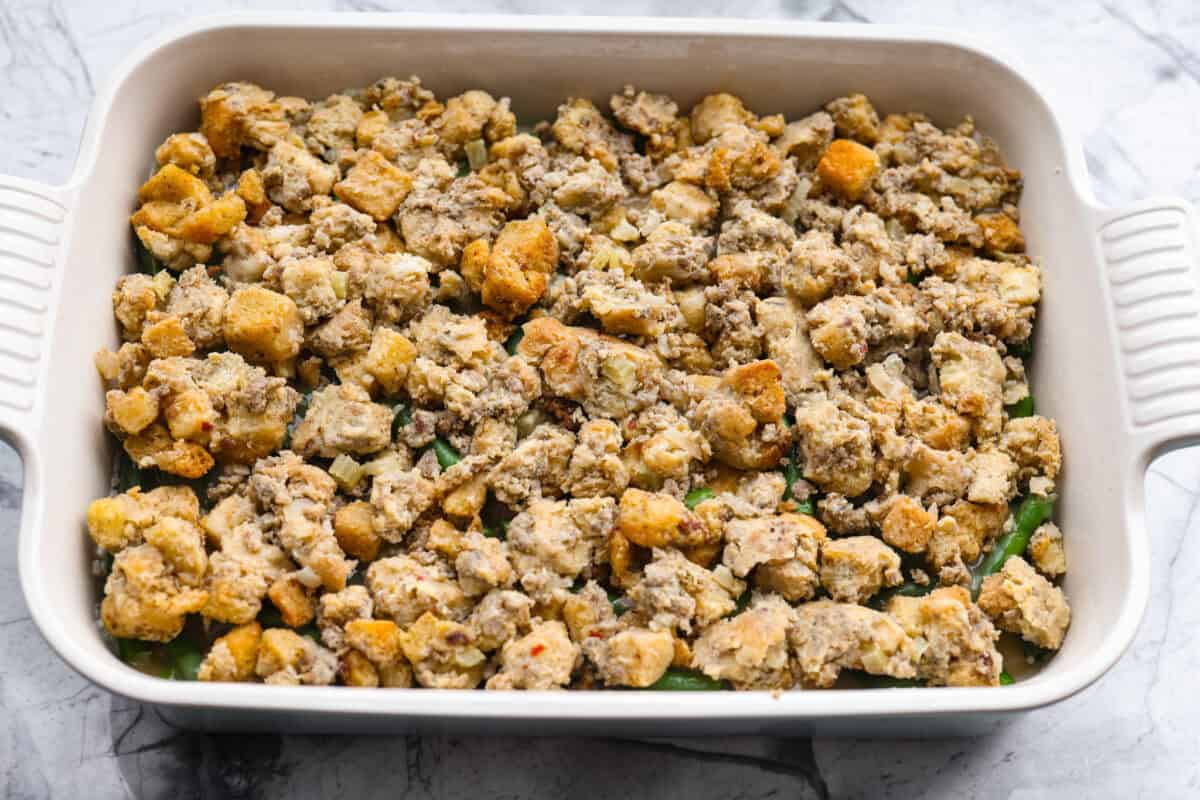 This Thanksgiving leftover casserole is the best way to enjoy every last bit of your holiday meal. I give you tips for keeping it moist, flavorful, and perfectly layered. Stuffing added to the top of the gravy covered green beans.