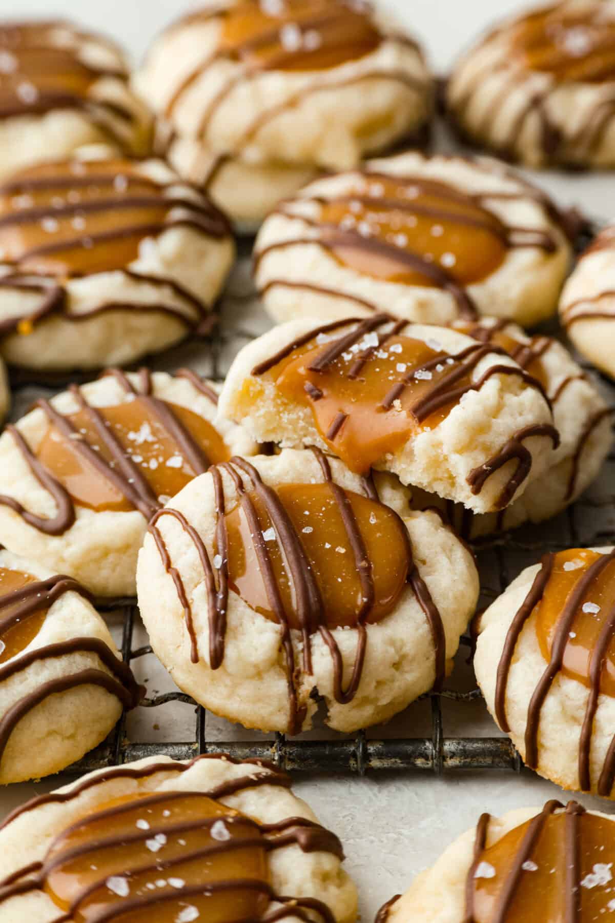 Side shot of completely baked and topped Twix thumbprint cookies on a cooling rack.