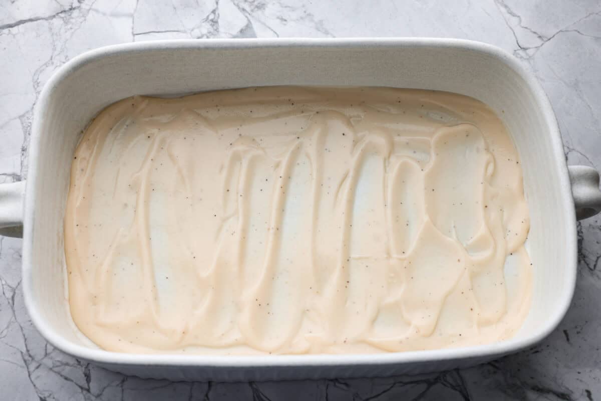 By the end of the day, Iโm wiped and still somehow expected to make dinner. I'm telling you, this Alfredo ravioli casserole will swoop in and save the day! Simply layer, bake, and enjoy! Alfredo sauce spread on the bottom of the baking dish.
