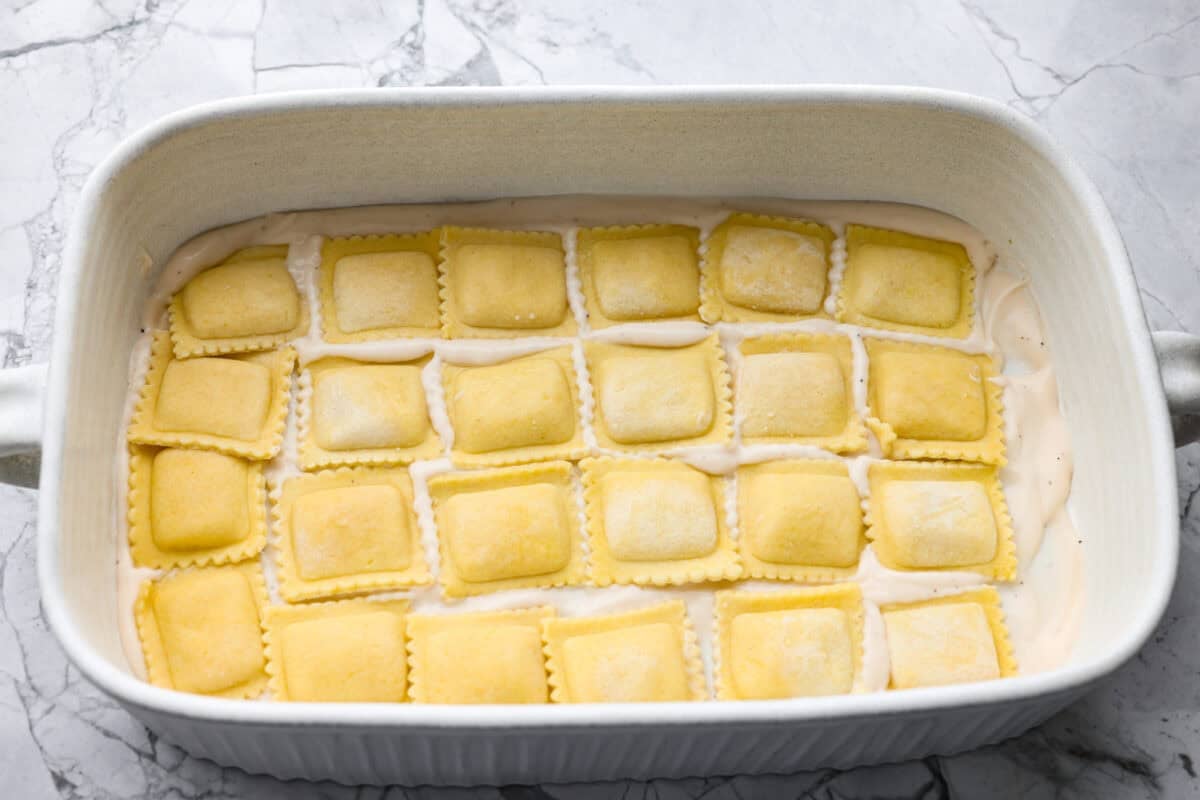 Frozen ravioli spread in an even layer on top of the sauce.
