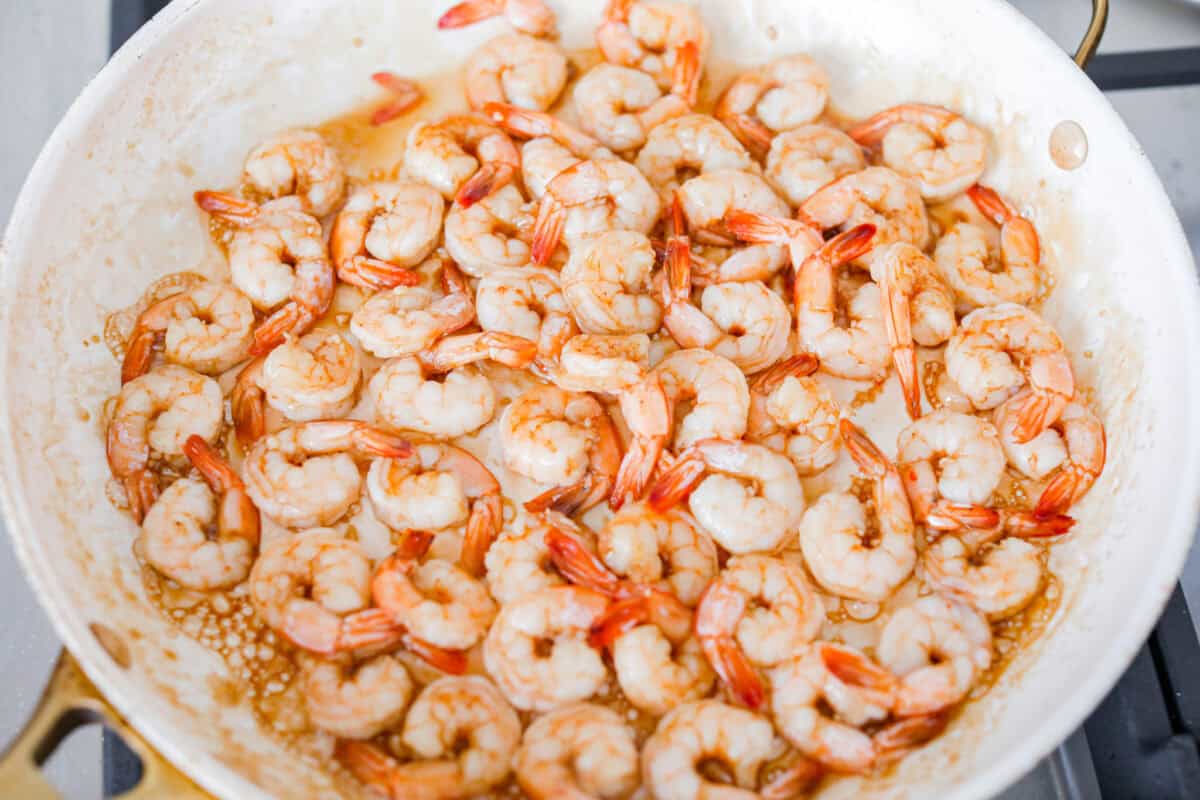 Bourbon shrimp are sticky, garlicky, and packed with flavor. Sweet brown sugar and a splash of bourbon create a quick, glossy glaze that makes this appetizer (or weeknight dinner!) totally irresistible. Shrimp cooking in a skillet.