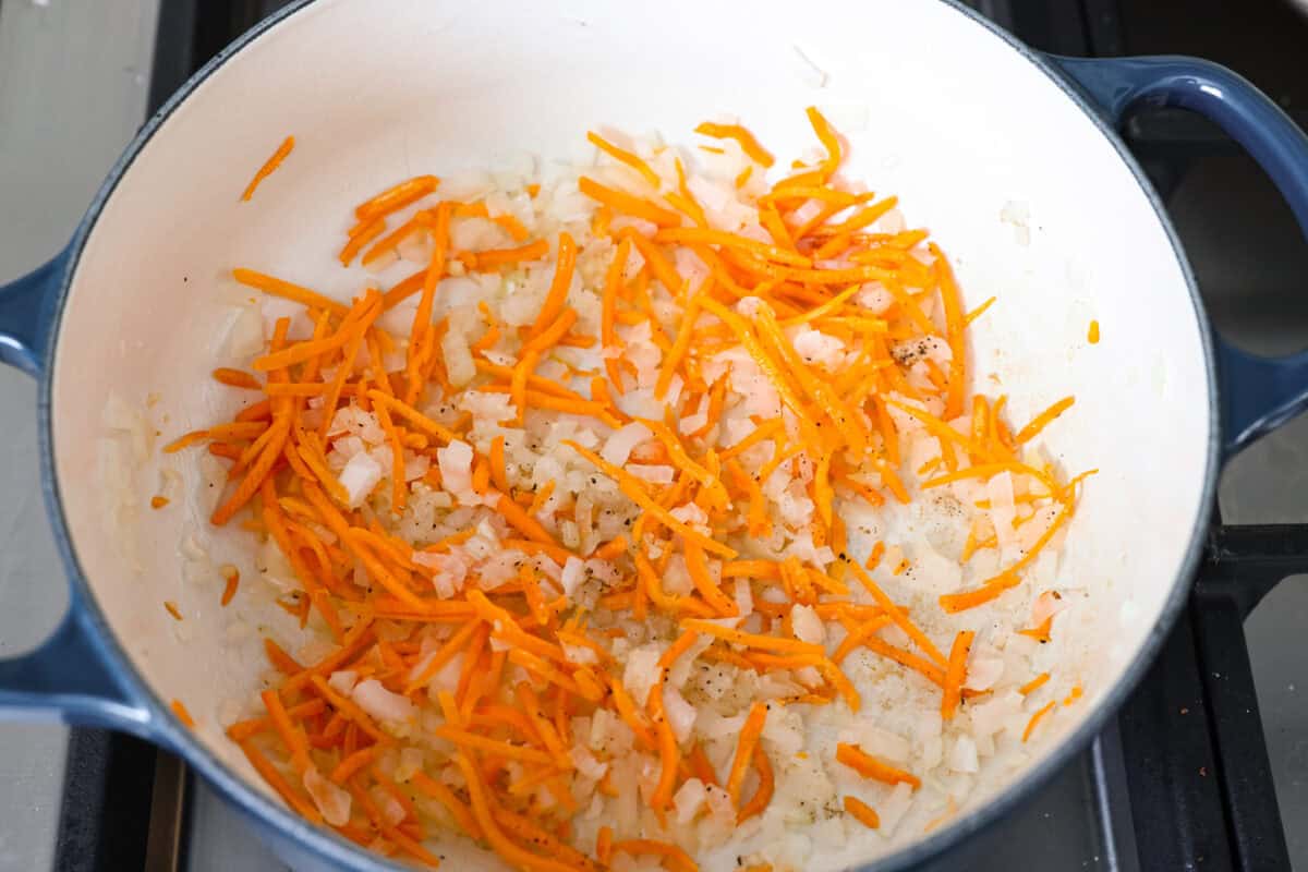 You guys are obsessed with my Broccoli Cheddar soup, and I know you love a good orzo recipe. So this simple, one-pot, ready-in-30-minute Broccoli Cheddar Orzo was born! Onions, carrots, and garlic cooking in a pan.