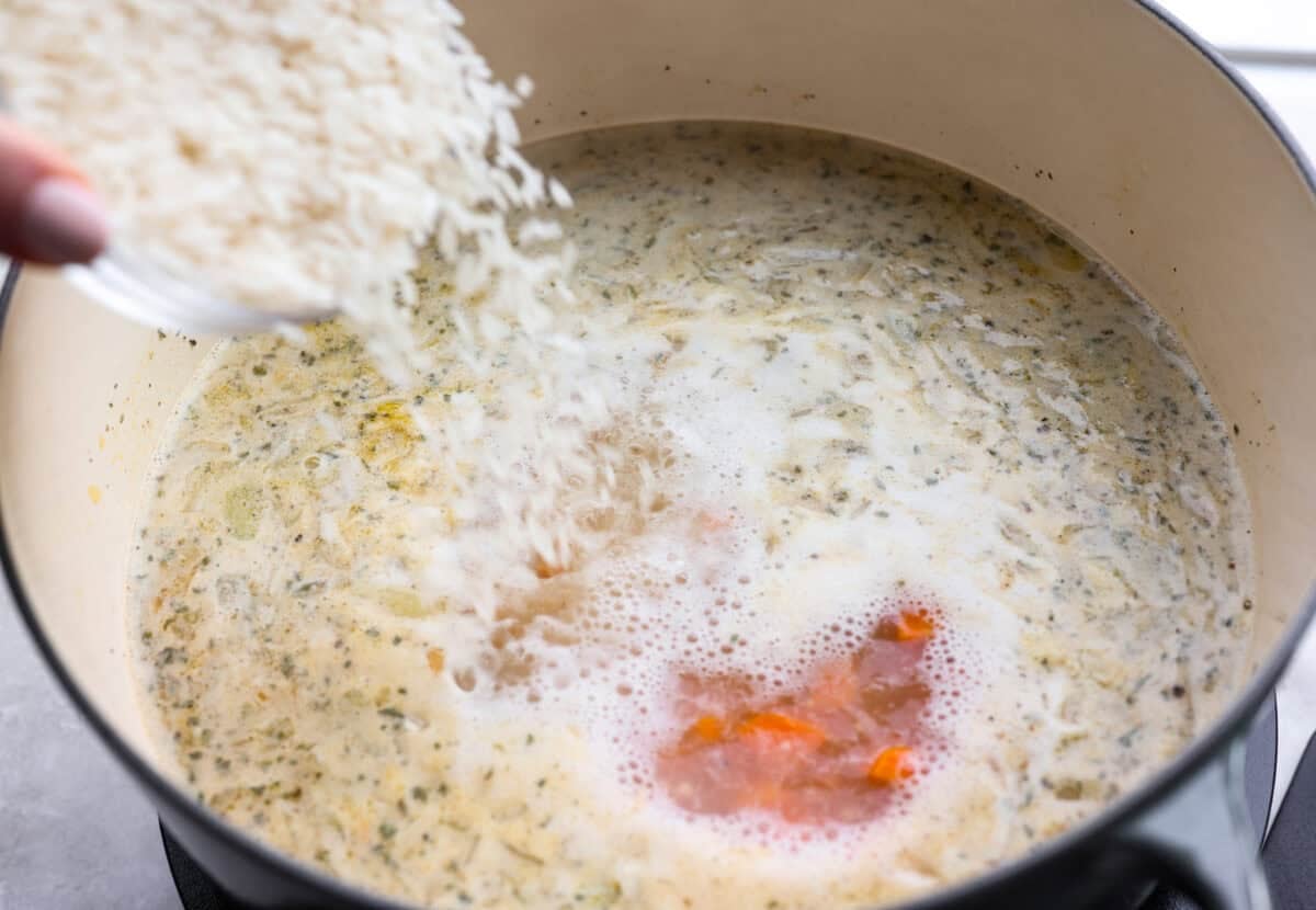 Stop what you are doing right now, and make this Crack Chicken and Rice soup! With tender chicken, rice, creamy cheese, crispy bacon, and bold ranch flavor, this easy one pot recipe tastes like pure comfort in every spoonful. Someone pouring rice into the pot.