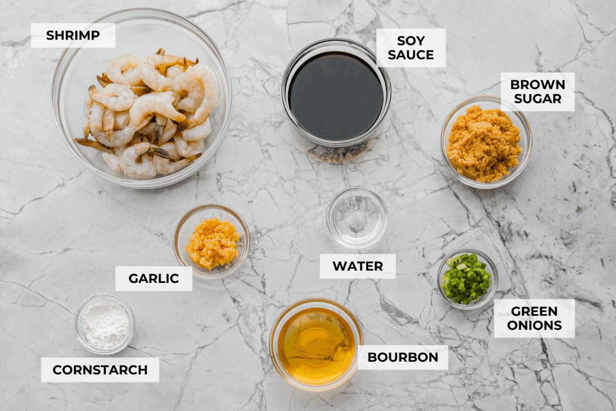 Bourbon shrimp are sticky, garlicky, and packed with flavor. Sweet brown sugar and a splash of bourbon create a quick, glossy glaze that makes this appetizer (or weeknight dinner!) totally irresistible. Overhead shot of labeled ingredients.