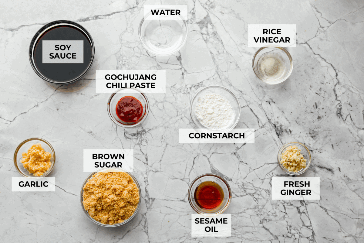 Korean BBQ sauce is the kind of pantry staple that turns random weeknight ingredients into something irresistible. Use it to glaze salmon, coat wings, toss with chicken and veggies, or turn into a killer Korean BBQ pizza Overhead shot of labeled Korean BBQ sauce ingredients.