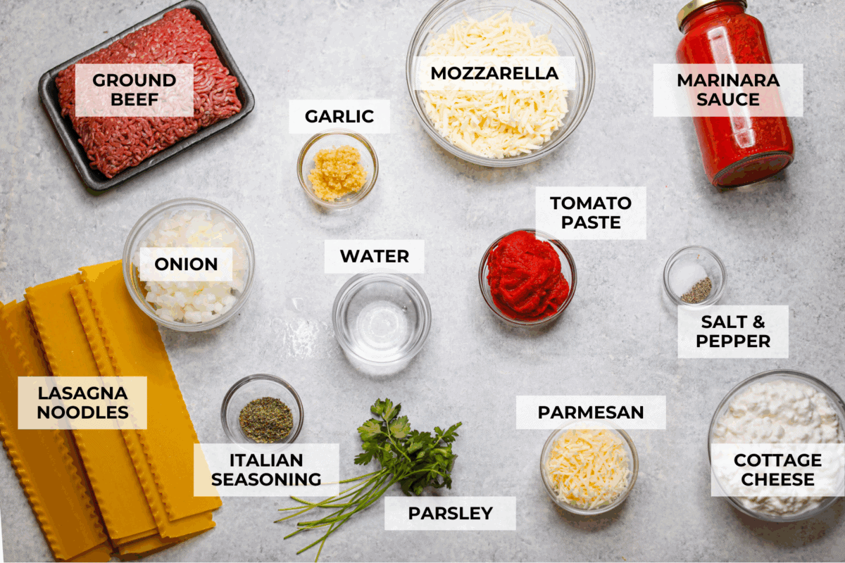 This easy slow cooker lasagna layers tender noodles with rich meat sauce and three cheeses, all with just 25 minutes of hands on prep. You get classic, cozy lasagna flavor that melds into every bite from slow cooking all day! Overhead shot of labeled slow cooker lasagna ingredients.