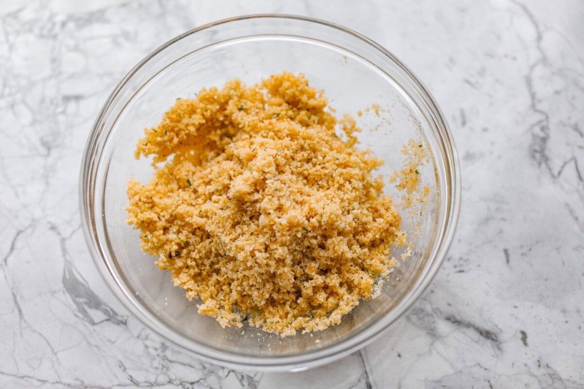My copycat Longhorn parmesan crusted chicken brings all the cheesy, buttery goodness from the restaurant straight to your kitchen. Juicy ranch chicken is topped with a creamy cheese sauce and a golden crumb crust. Breadcrumb topping mixed together in a bowl.