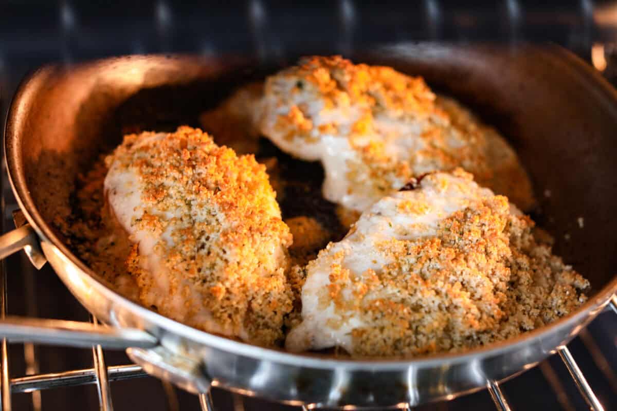 My copycat Longhorn parmesan crusted chicken brings all the cheesy, buttery goodness from the restaurant straight to your kitchen. Juicy ranch chicken is topped with a creamy cheese sauce and a golden crumb crust. Longhorn parmesan crusted chicken in the skillet placed in the oven to broil.