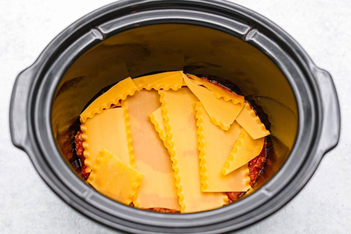 This easy slow cooker lasagna layers tender noodles with rich meat sauce and three cheeses, all with just 25 minutes of hands on prep. You get classic, cozy lasagna flavor that melds into every bite from slow cooking all day! Lasagna noodles layered on top of the meat sauce.