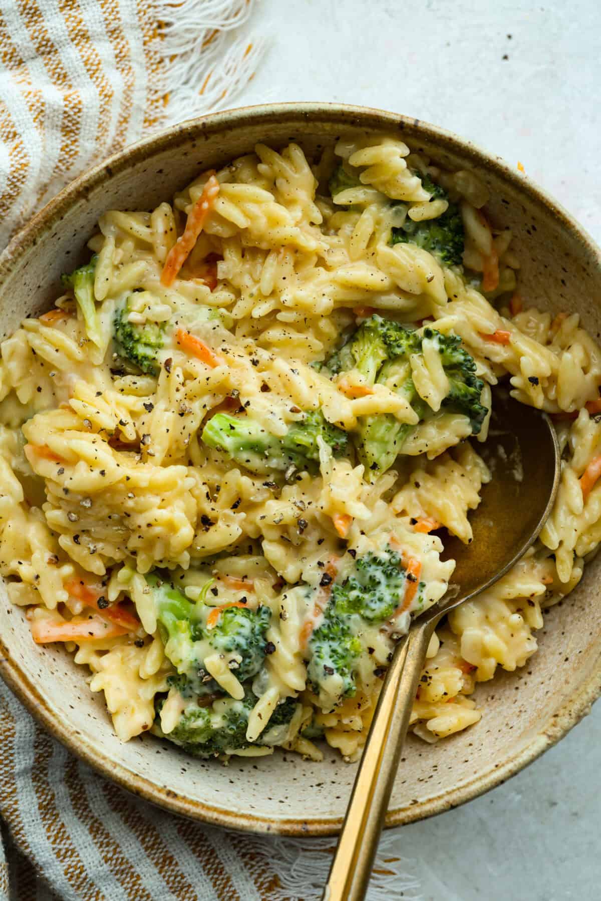 You guys are obsessed with my Broccoli Cheddar soup, and I know you love a good orzo recipe. So this simple, one-pot, ready-in-30-minute Broccoli Cheddar Orzo was born! Broccoli cheddar orzo serving in a dish.