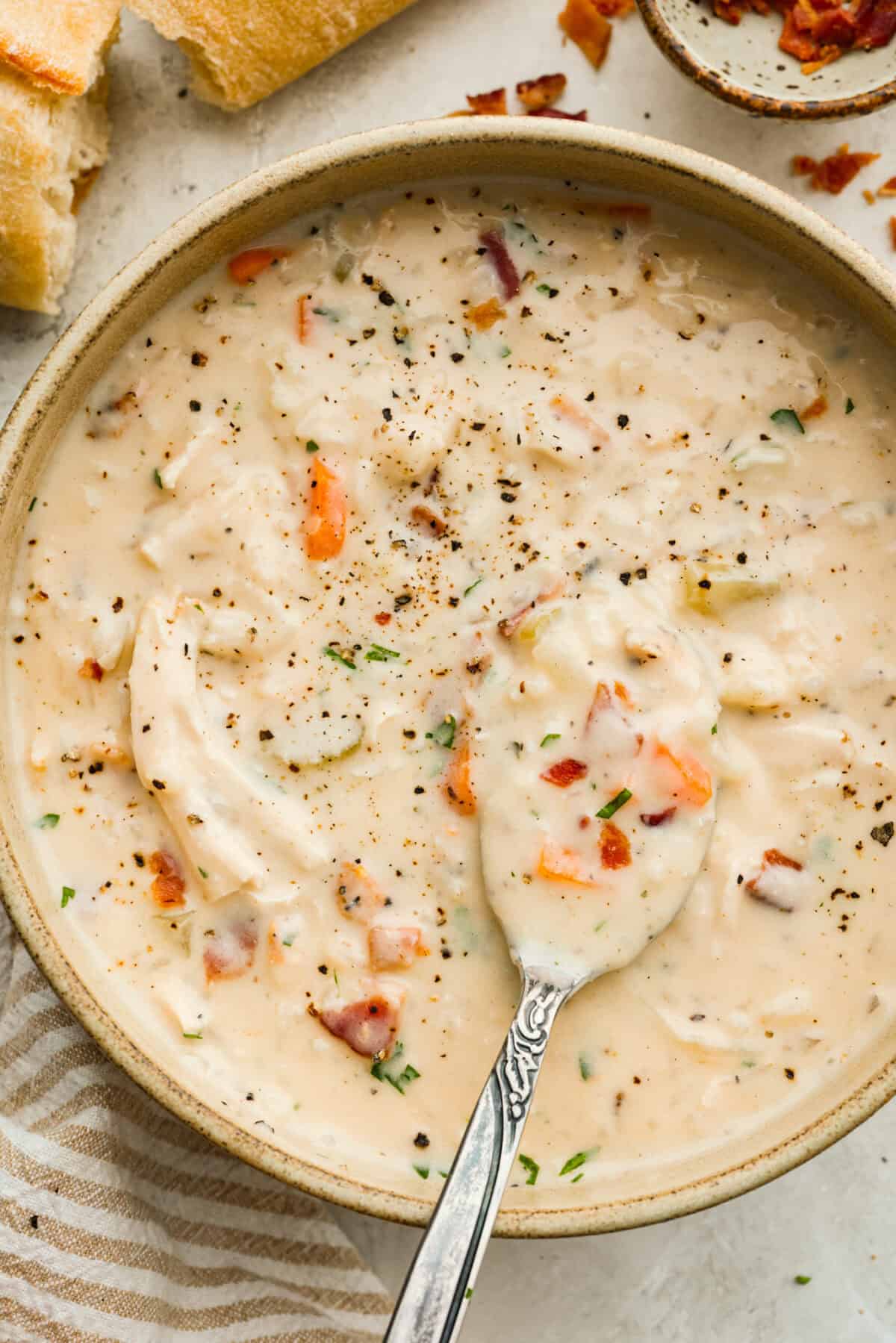 Bowl of crack chicken and rice soup with a spoon lifting a bite out.