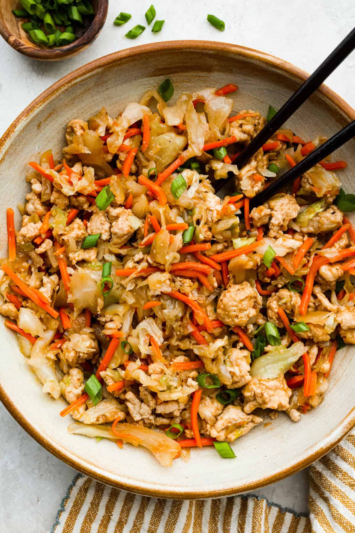 If you havenโt tried egg roll in a bowl yet, youโre in for a treat. Everything you love inside of an egg roll in a lighter, healthier, no-wrapper version! It's ready in 15 minutes, making it a perfect weeknight meal! Serving portion of egg roll in a bowl with chopsticks.