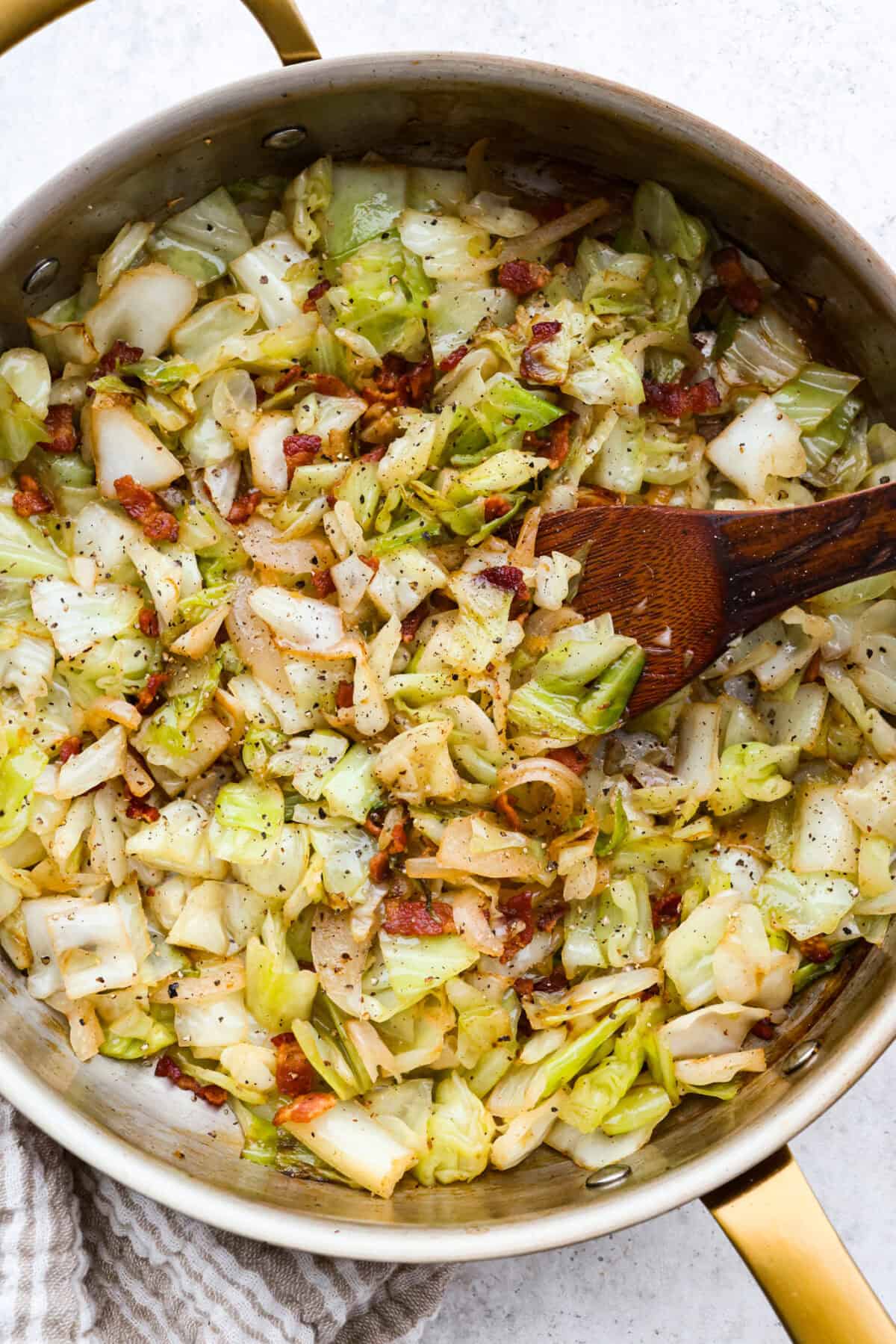 You donโt need fancy ingredients to make something great, and this fried cabbage proves that! Bacon, cabbage, a little seasoning, and a hot skillet. Thatโs it. And it works every single time. Overhead shot of fried cabbage in the skillet with a wooden spoon.