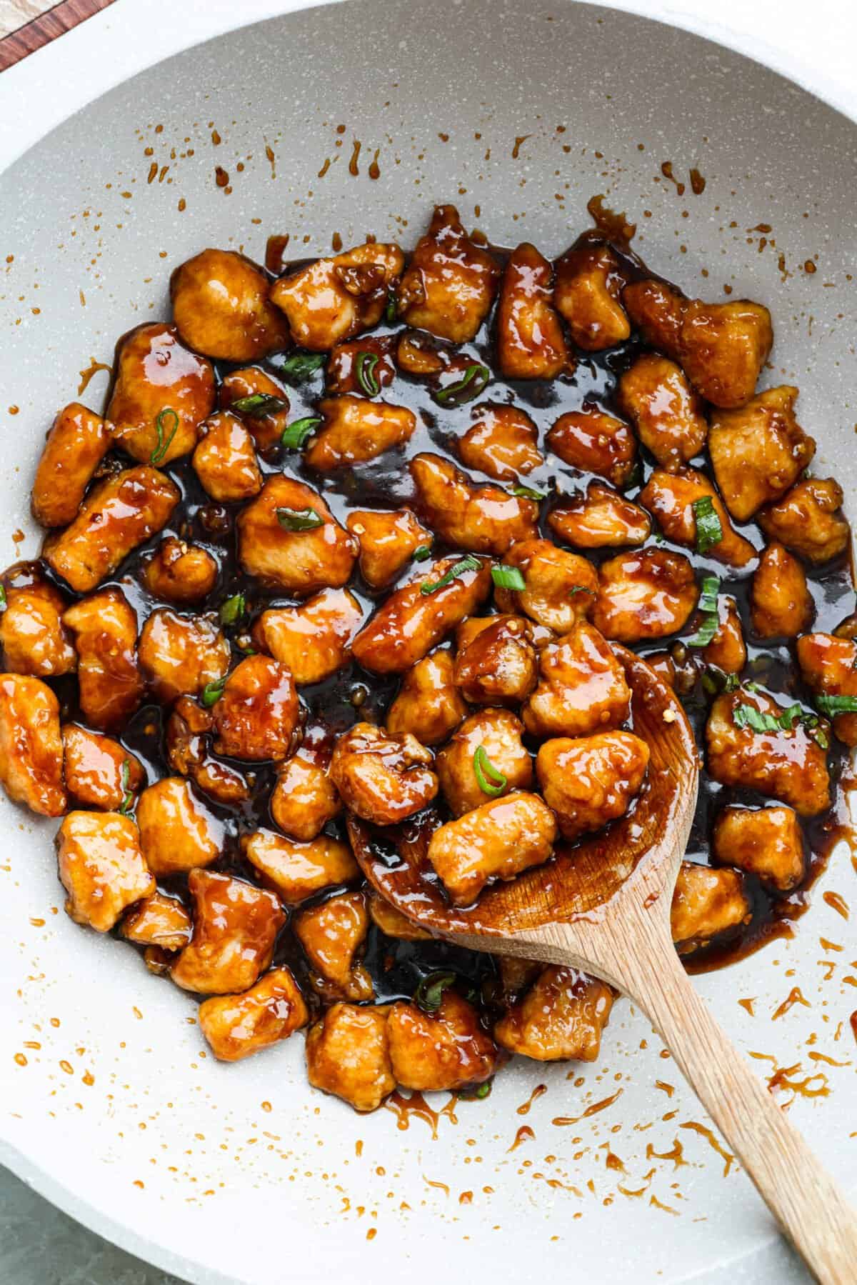You love my baked General Tso’s chicken, so obviously, I had to make a faster one. This one pan General Tso's chicken is sticky, saucy, and on the table in about 30 minutes. One pan general Tso's chicken in a skillet with a wooden spoon.