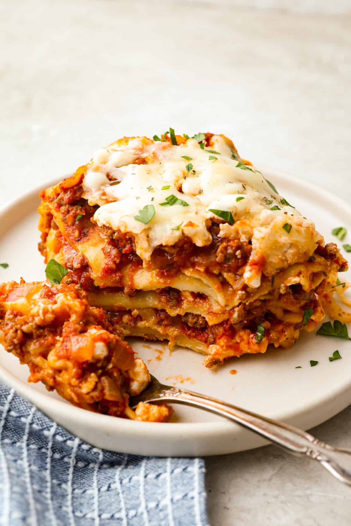 This easy slow cooker lasagna layers tender noodles with rich meat sauce and three cheeses, all with just 25 minutes of hands on prep. You get classic, cozy lasagna flavor that melds into every bite from slow cooking all day! Plated portion of slow cooker lasagna.