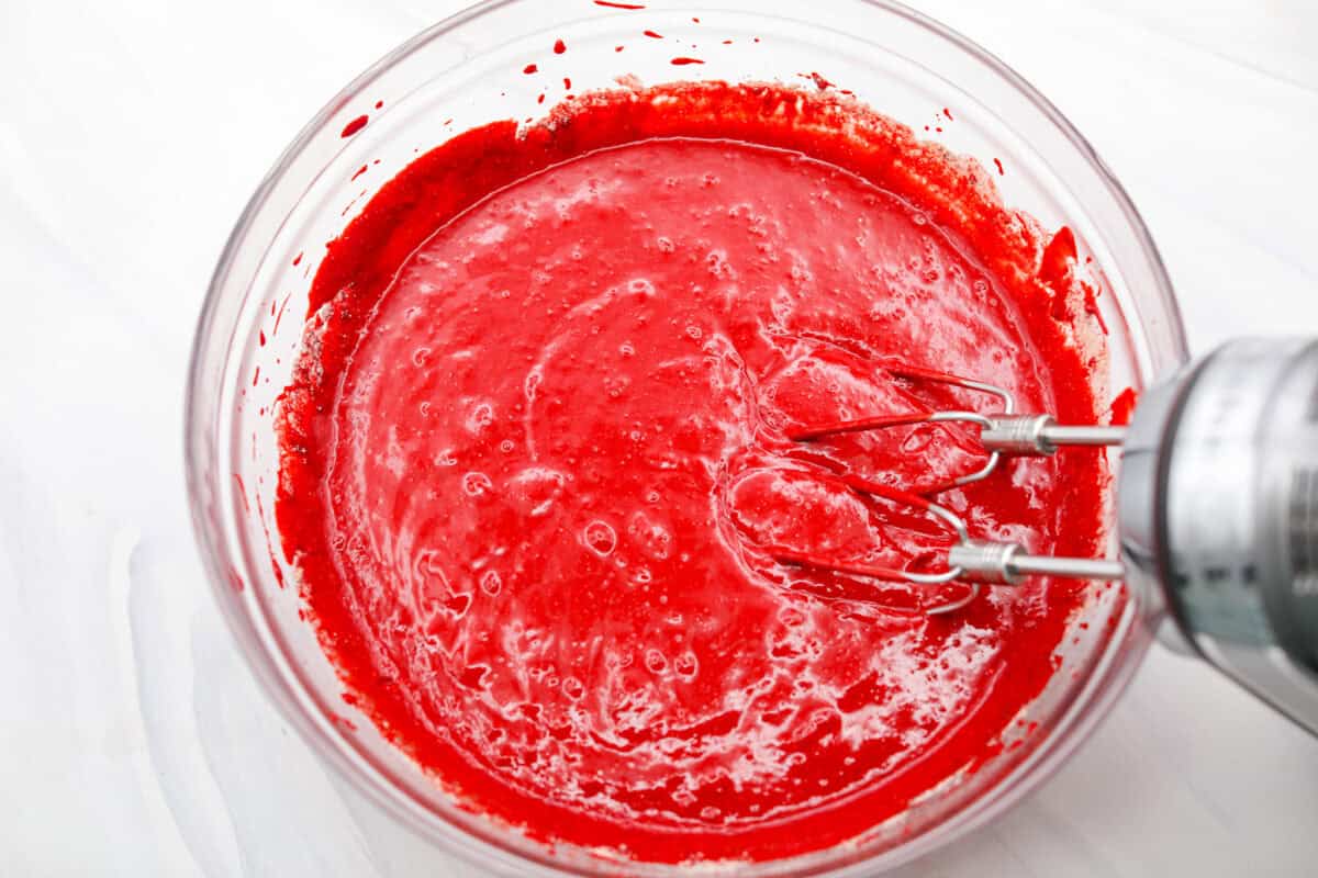 This 2-ingredient red velvet cake is almost too easy to believe! With just a cake mix and a can of soda, you can make a soft, fluffy cake in minutes. It’s the perfect shortcut dessert for Valentine’s Day or any sweet craving! Someone using an electric hand mixer to mix the cake mix and soda together.