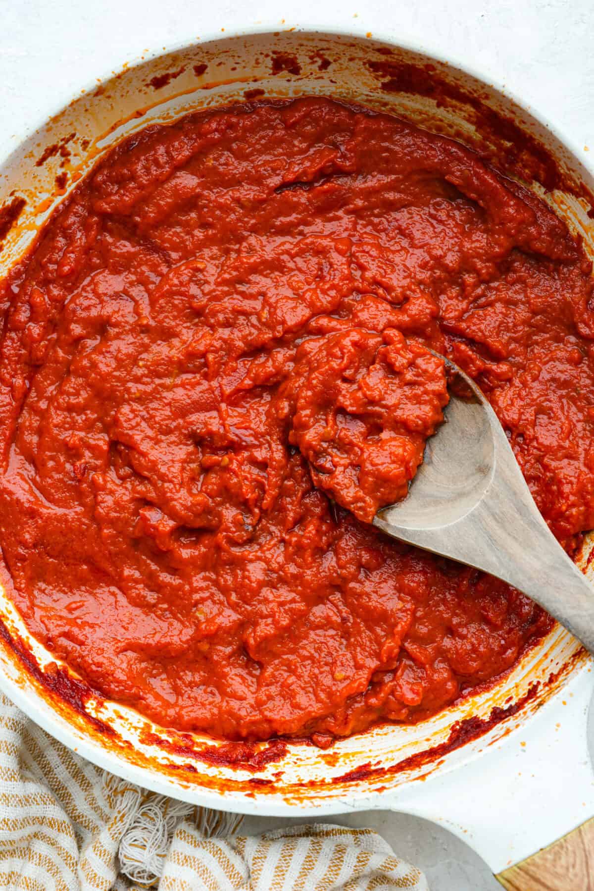 Simple, classic, and downright magical, this iconic Marcella Hazan's tomato sauce uses only 3 ingredients and proves that less is more. With just tomatoes, butter, and onion, it turns pantry staples into a rich, silky sauce you’ll make on repeat. Marcella Hazan's tomato sauce with a wooden spoon in a sauce pan.