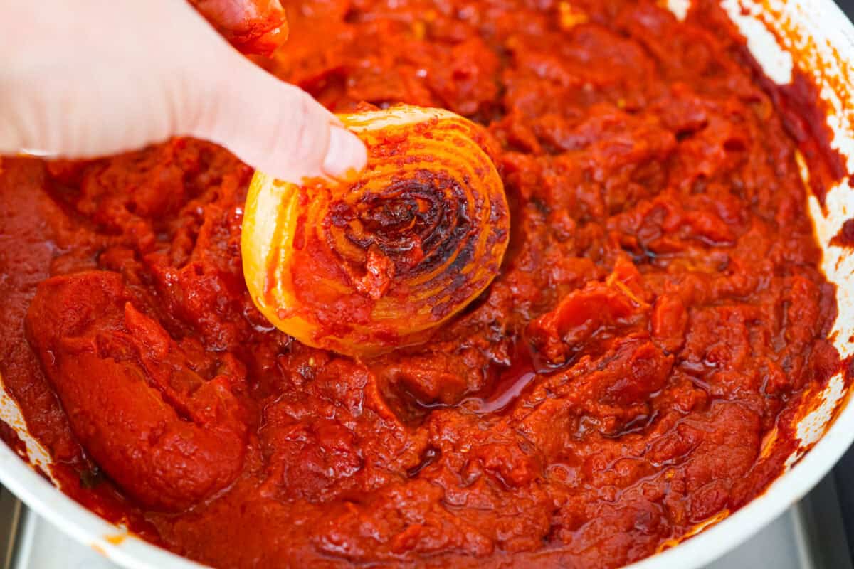 Simple, classic, and downright magical, this iconic Marcella Hazan's tomato sauce uses only 3 ingredients and proves that less is more. With just tomatoes, butter, and onion, it turns pantry staples into a rich, silky sauce you’ll make on repeat. Someone taking the onions out of the sauce.