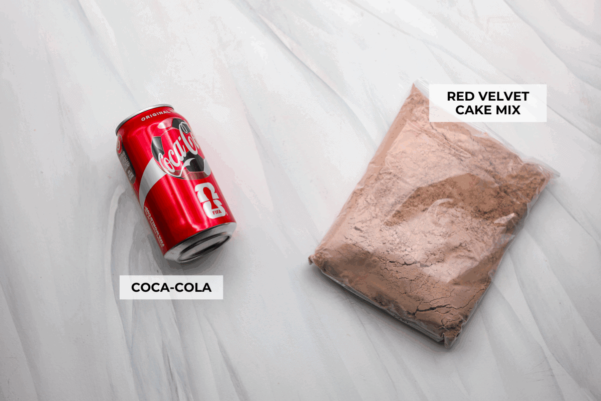 This 2-ingredient red velvet cake is almost too easy to believe! With just a cake mix and a can of soda, you can make a soft, fluffy cake in minutes. It’s the perfect shortcut dessert for Valentine’s Day or any sweet craving! Overhead shot of labeled 2 ingredient red velvet cake ingredients.