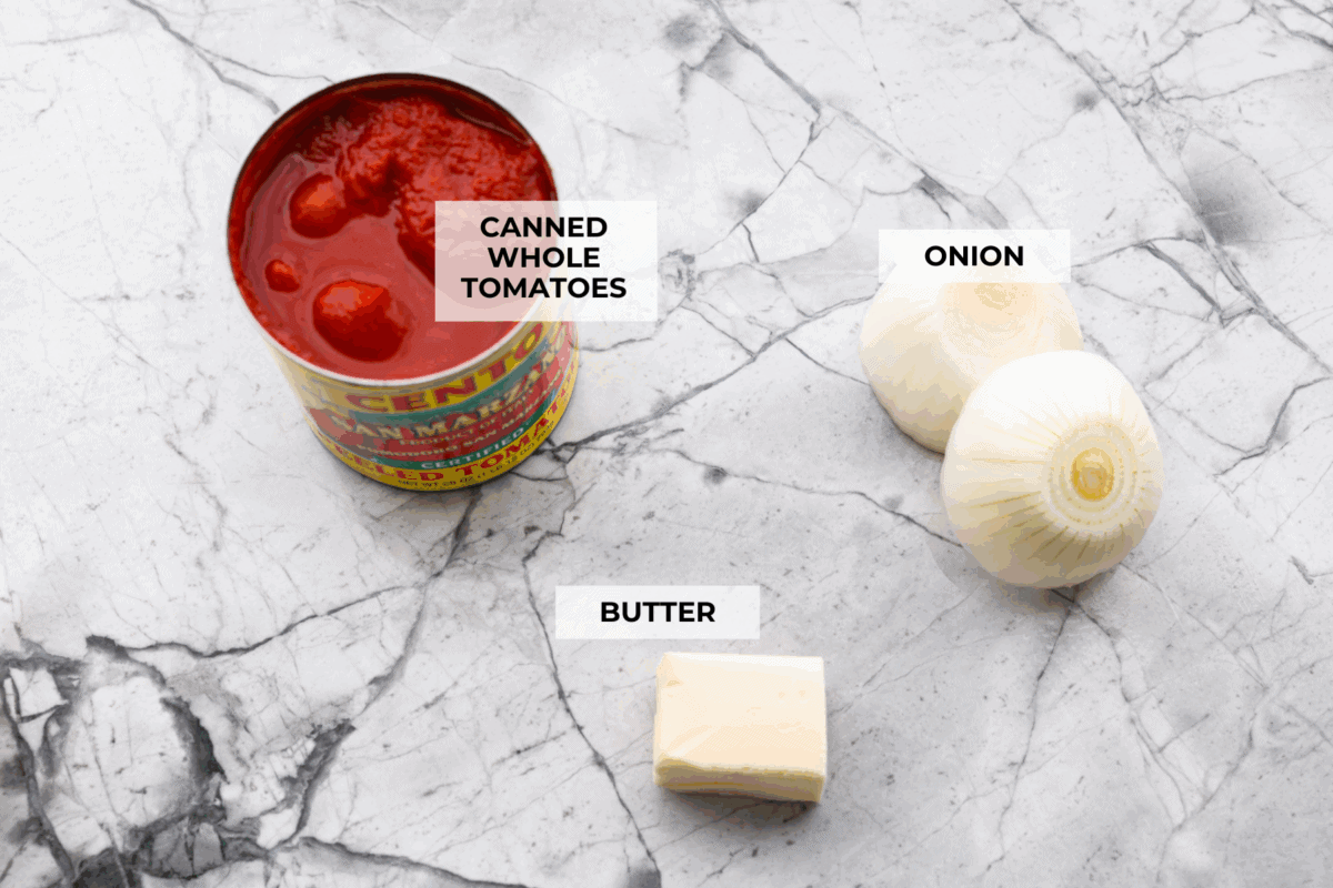 Simple, classic, and downright magical, this iconic Marcella Hazan's tomato sauce uses only 3 ingredients and proves that less is more. With just tomatoes, butter, and onion, it turns pantry staples into a rich, silky sauce you’ll make on repeat. Overhead shot of labeled ingredients.